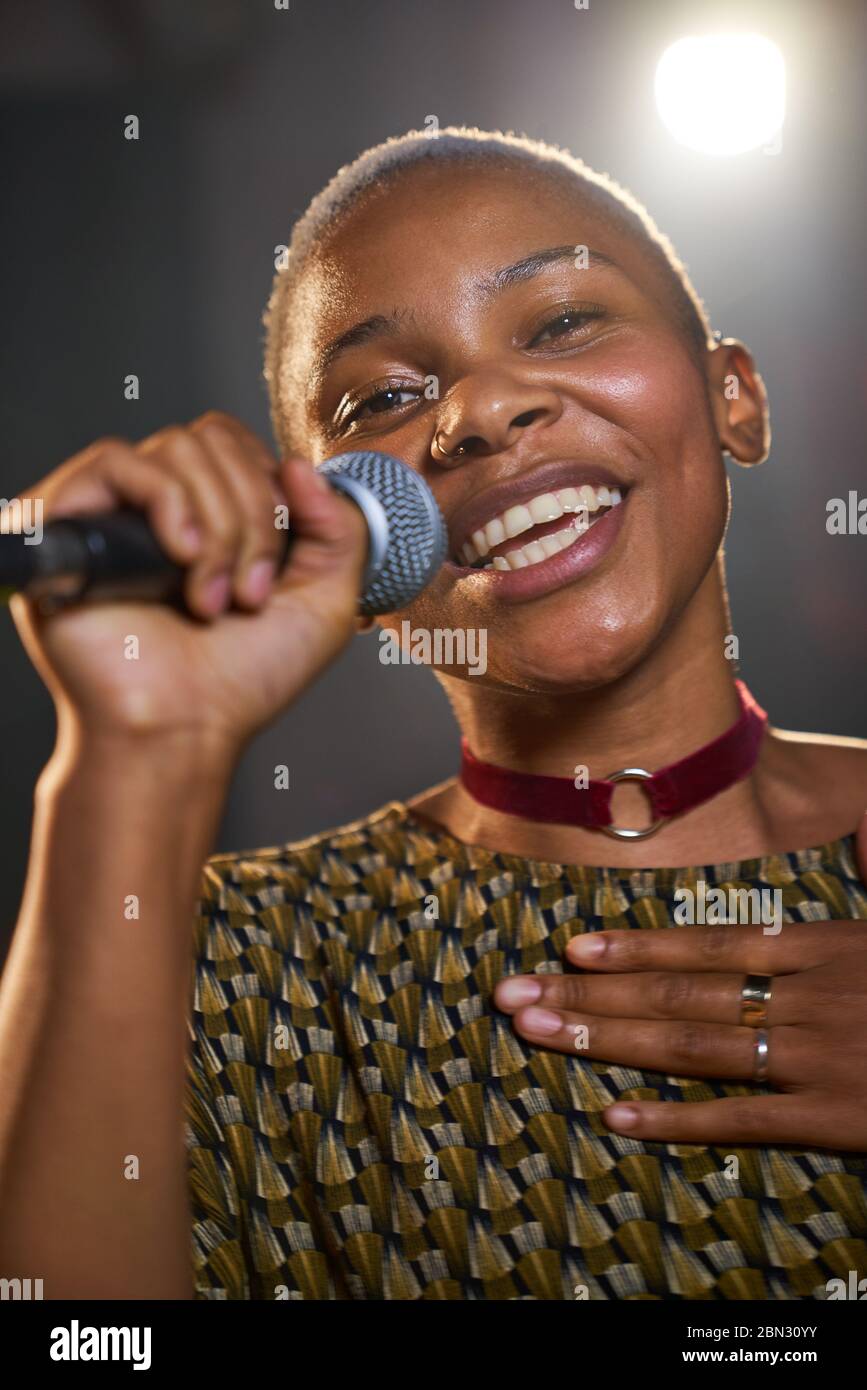 Portrait happy young female musician singing into microphone Stock Photo