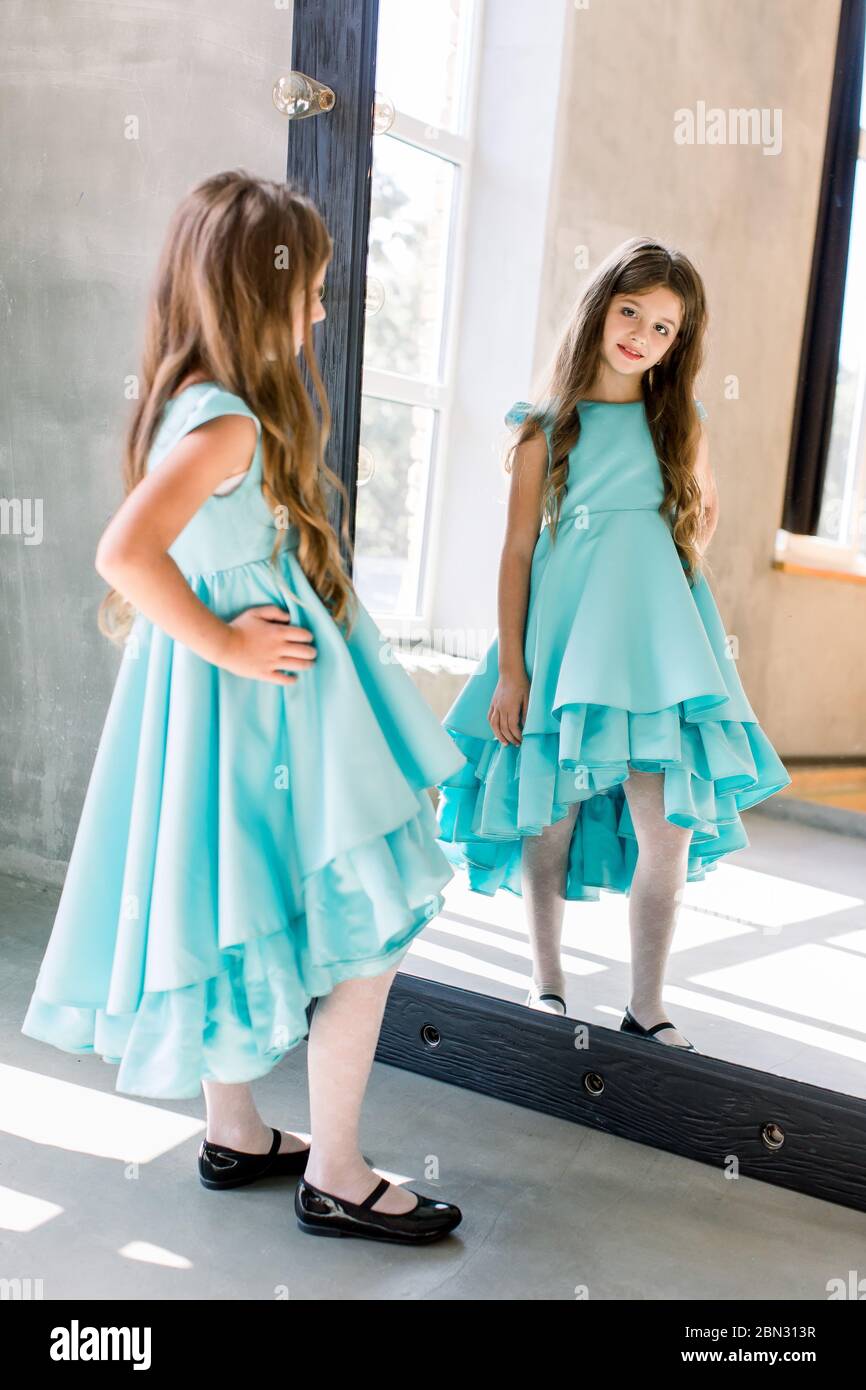 The lovely little girl posing in a beautiful blue dress is posing ...