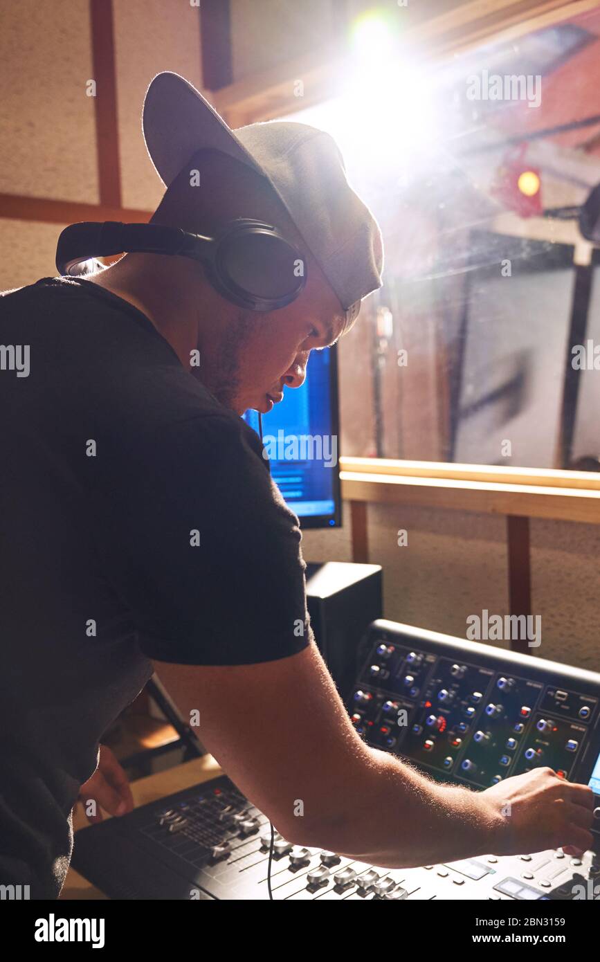Male music producer at sound board in recording studio Stock Photo