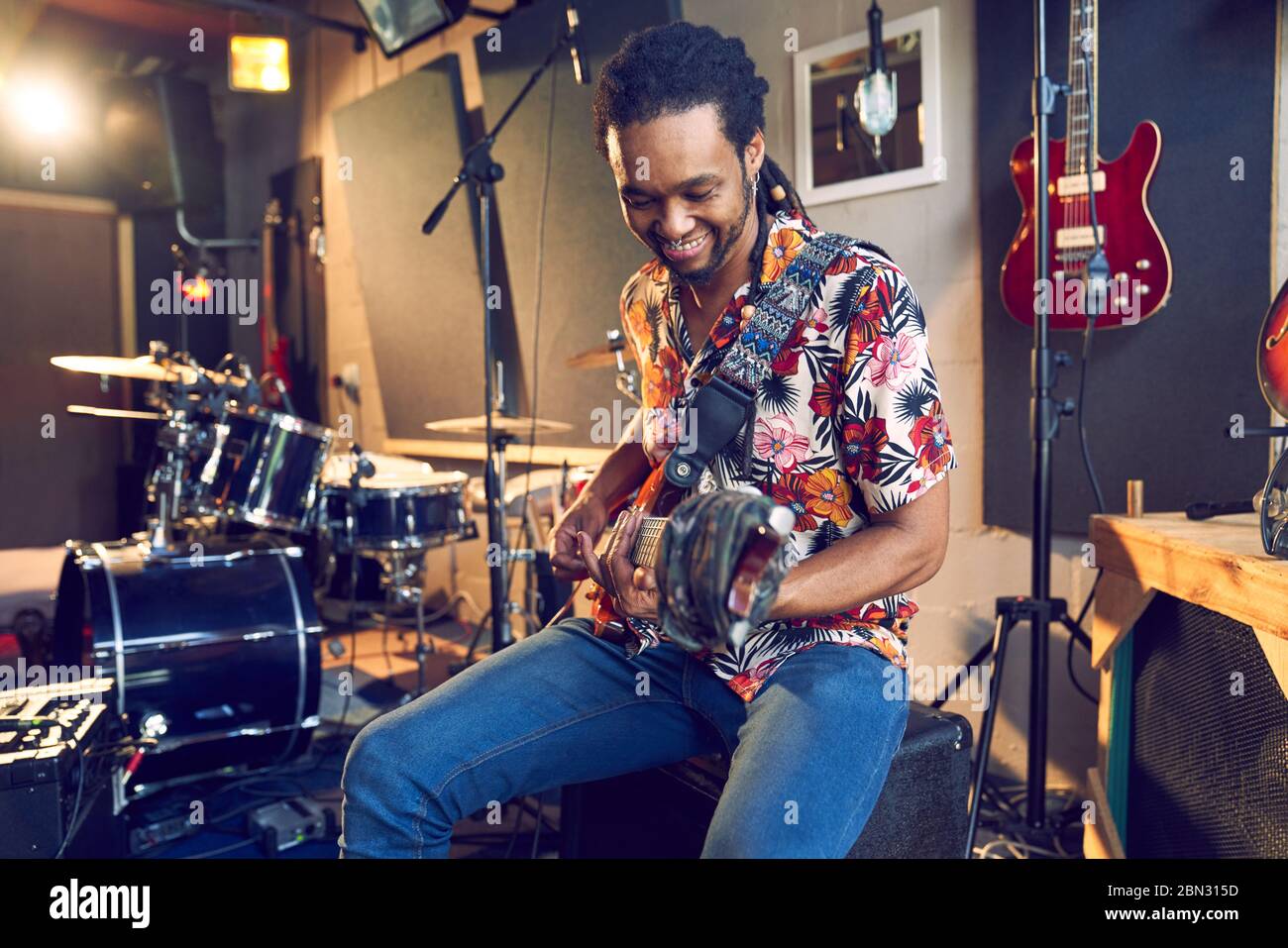 Male musician playing guitar in recording studio Stock Photo