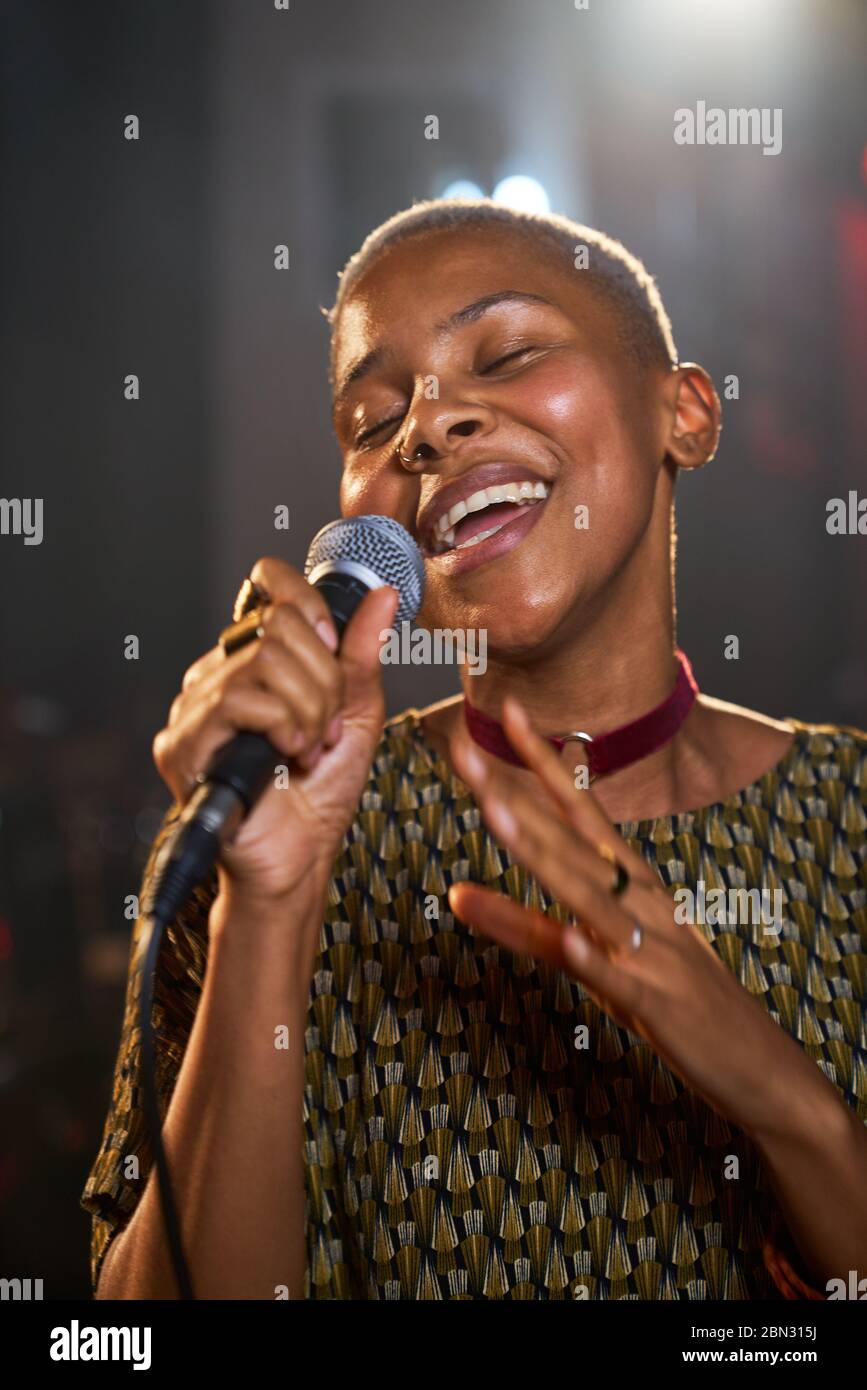 Young female musician singing into microphone Stock Photo - Alamy
