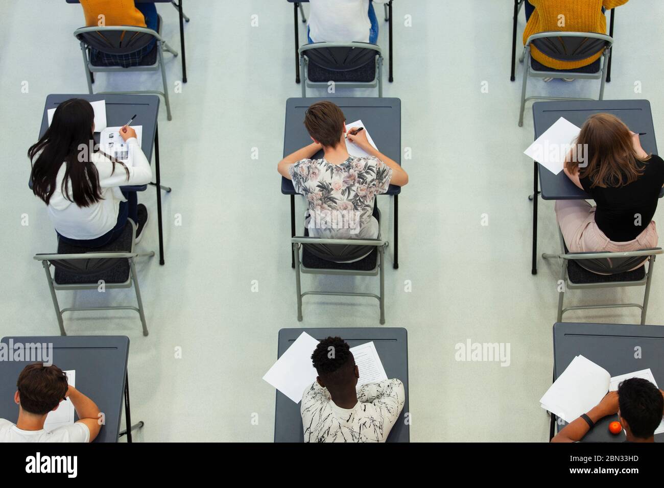 Overhead view high school students taking exam at desks in classroom Stock Photo