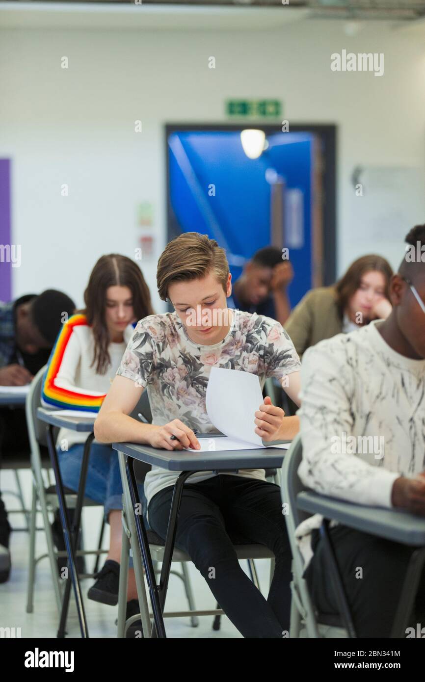 Focused high school boy student taking exam at desk in classroom Stock Photo