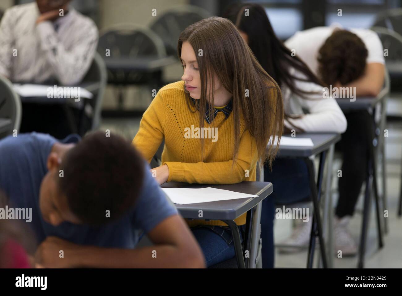 Focused high school girl student taking exam at desk in classroom Stock Photo