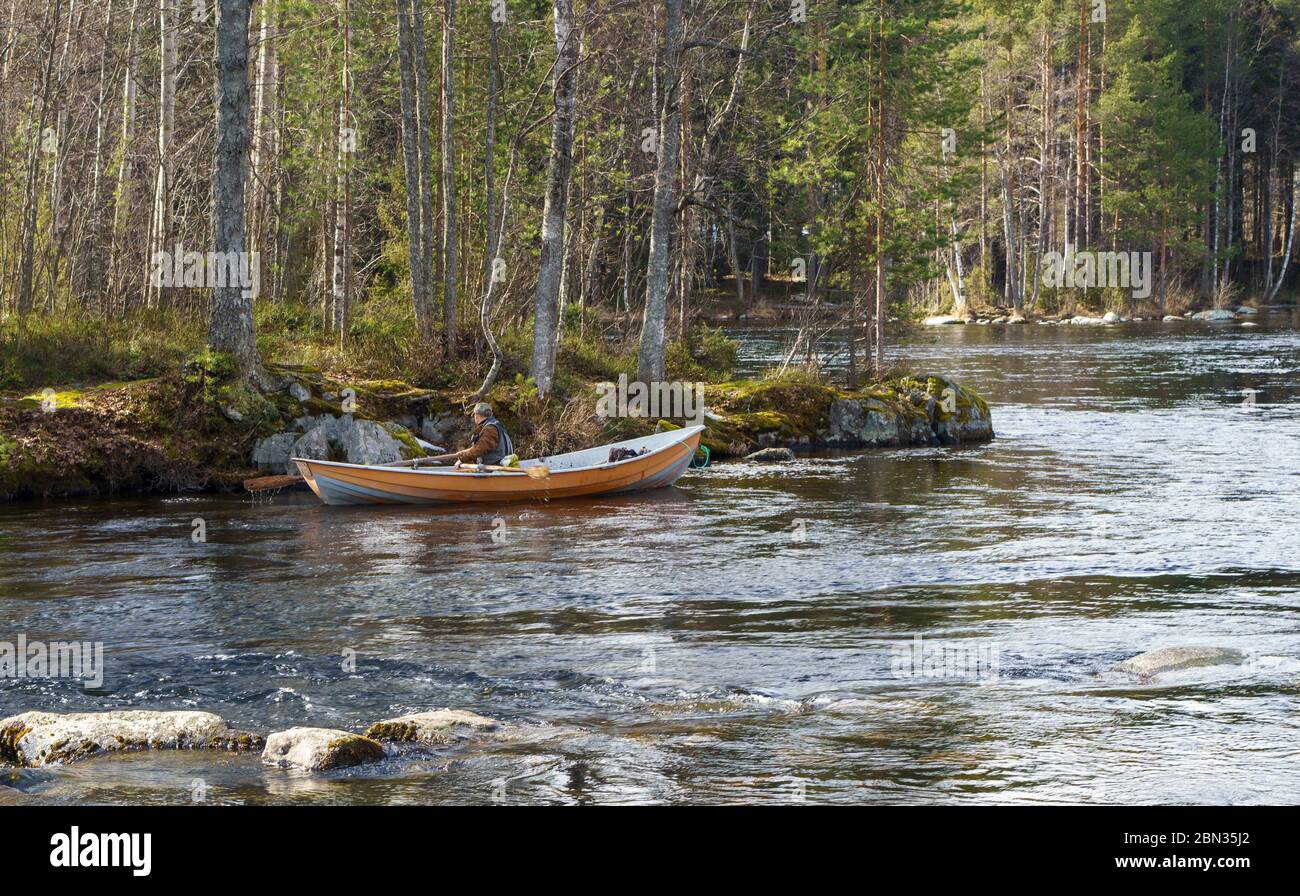 Fisherman trolling from rowboat / skiff at river Nokisenkoski , Finland Stock Photo