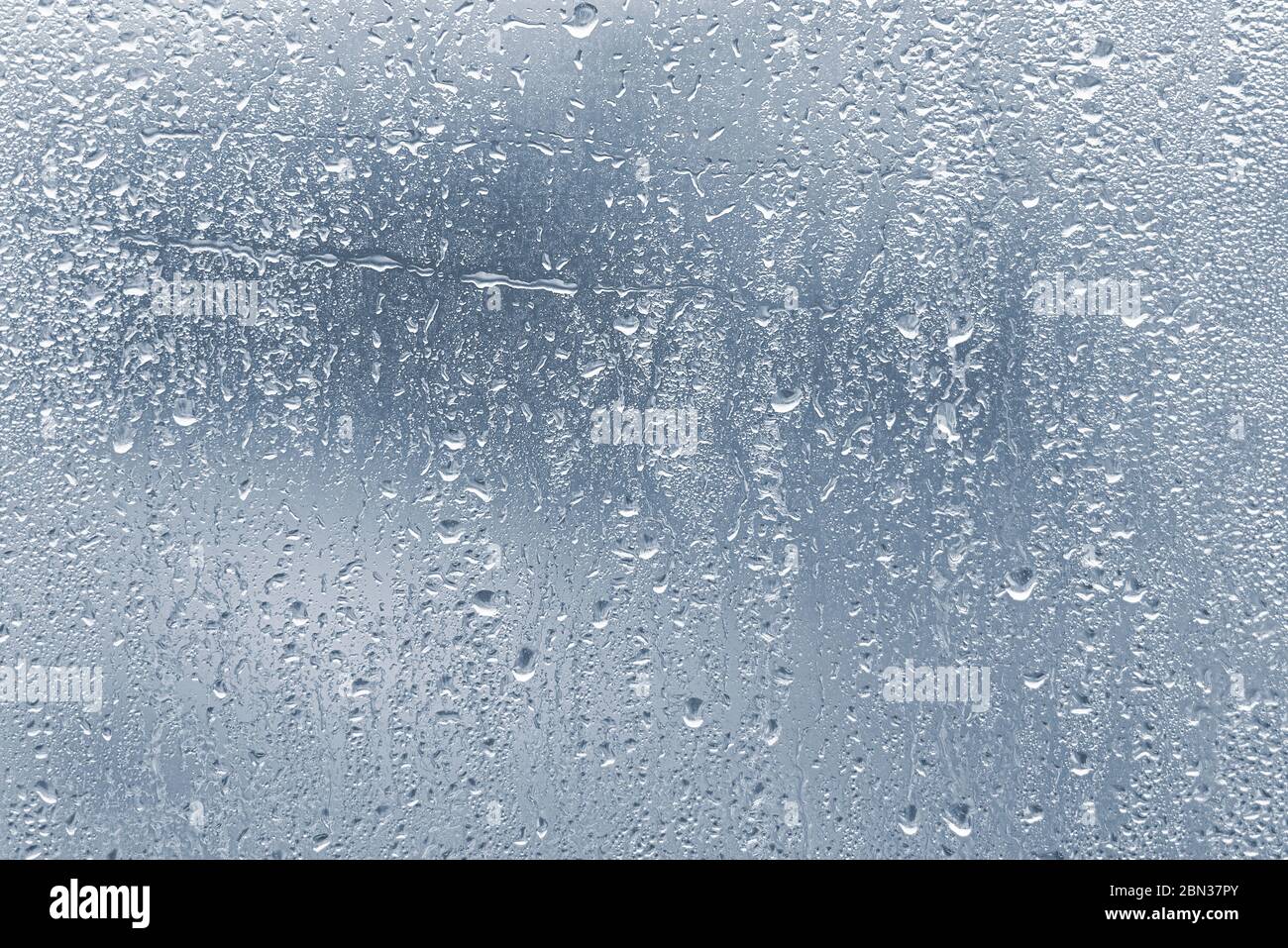 Raindrops, condensation on the glass window during heavy rain, water drops on blue glass Stock Photo