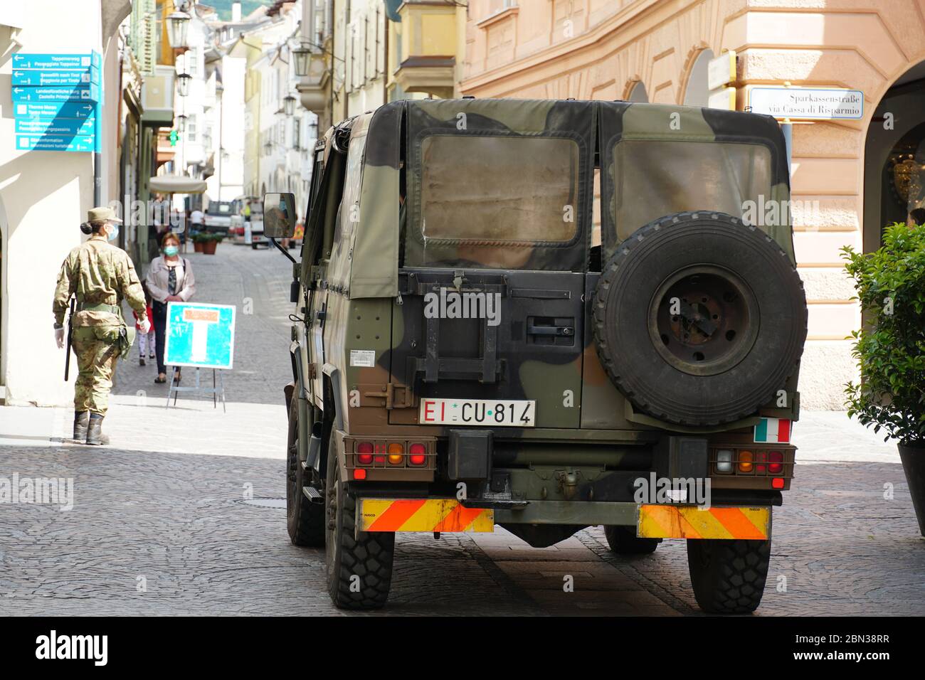 Army vehicle and walking soldiers on the street in Merano, South Tyrol, Italy, checking the city, patrolling after Italy has entered into Phase 2 Stock Photo