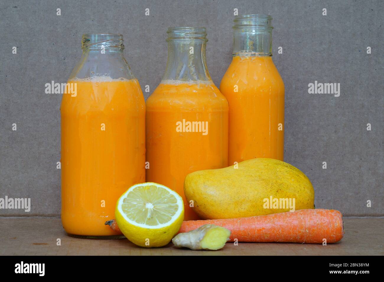 https://c8.alamy.com/comp/2BN38YM/glass-bottles-filled-with-colorful-fresh-homemade-mango-carrot-and-ginger-smoothies-2BN38YM.jpg