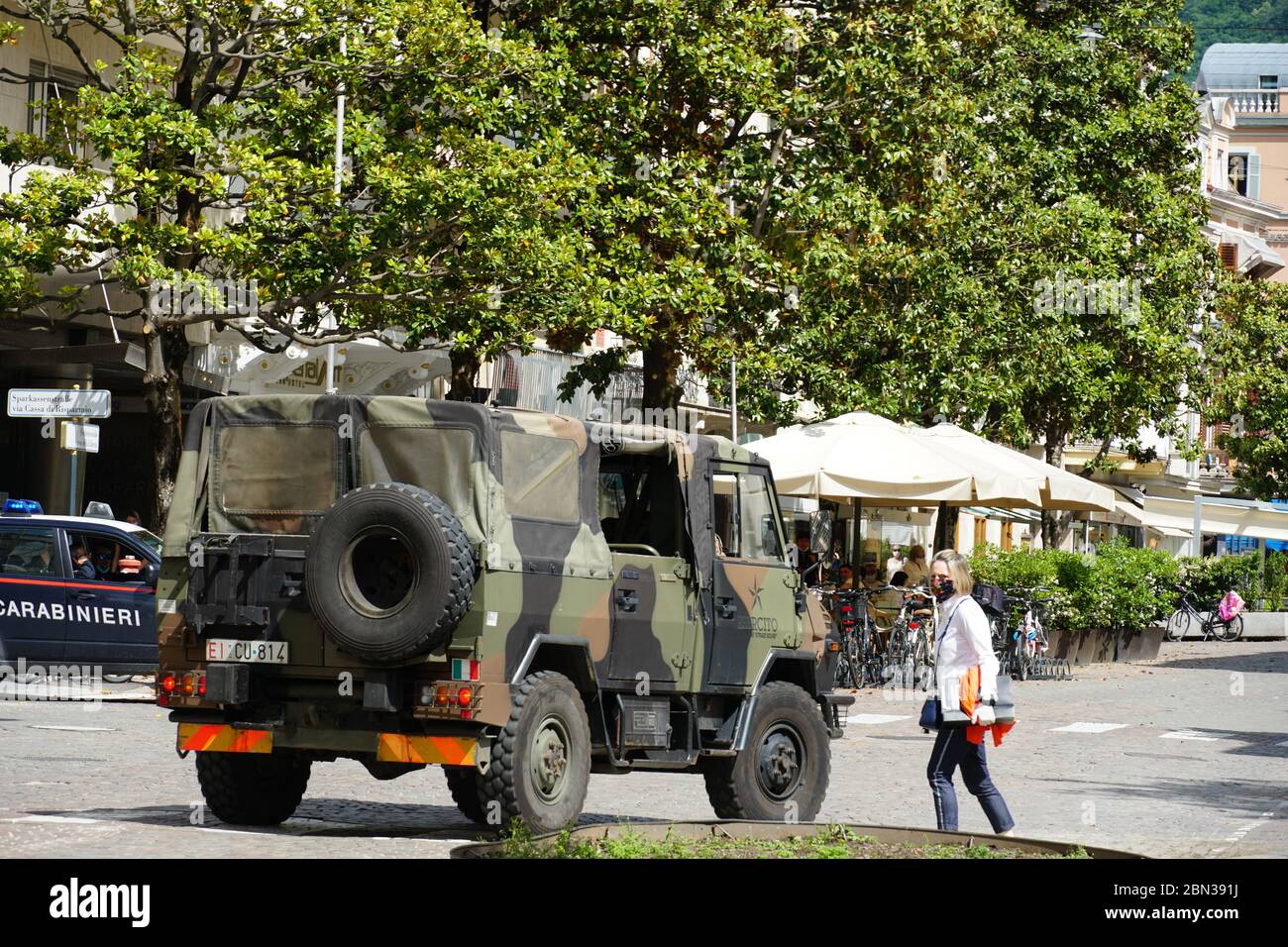 Army vehicle and walking soldiers on the street in Merano, South Tyrol, Italy, checking the city, patrolling after Italy has entered into Phase 2 Stock Photo