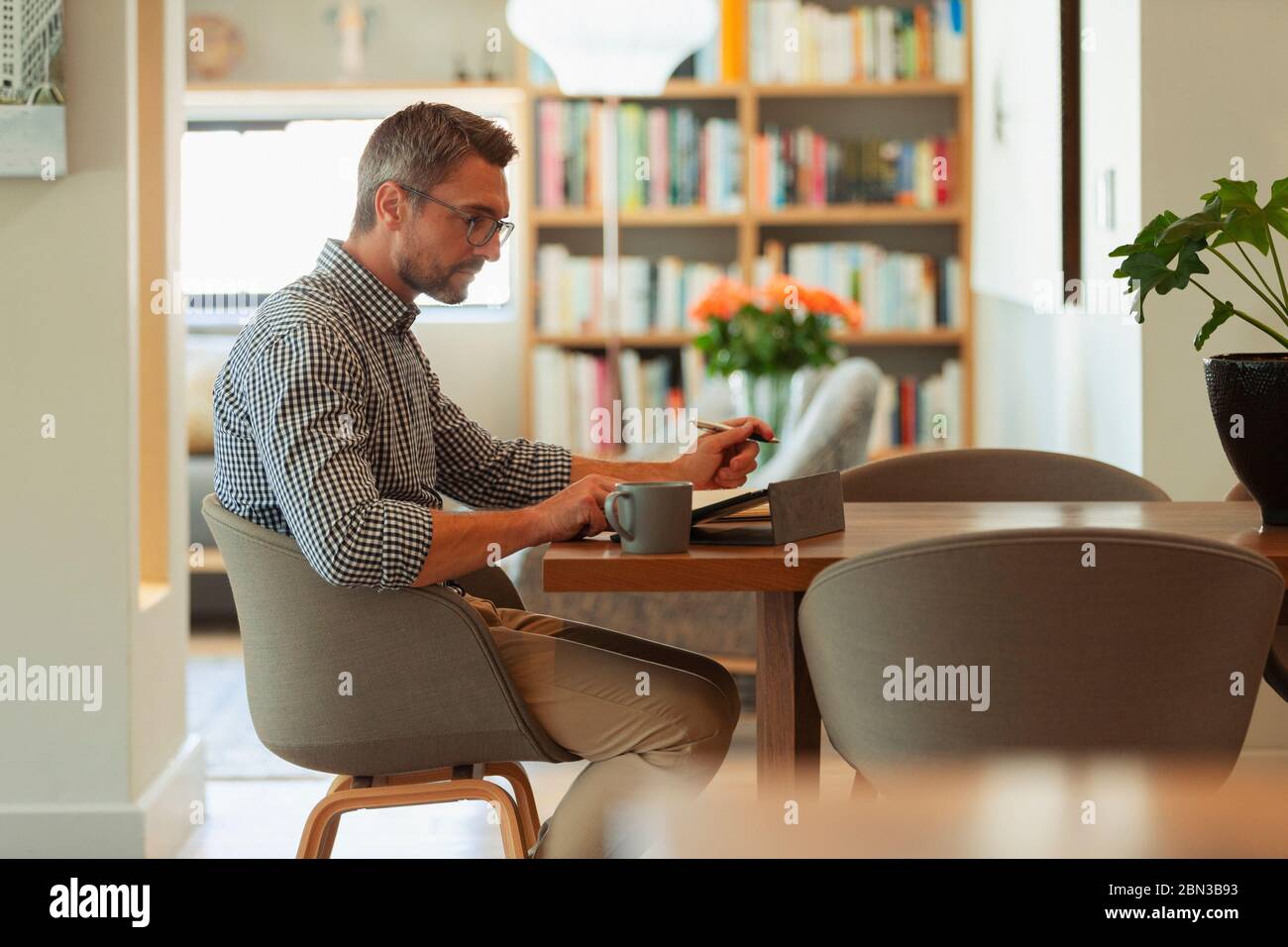 Businessman using digital tablet, working from home at dining table Stock Photo