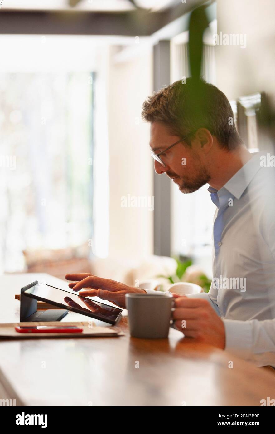 Businessman using digital tablet and drinking coffee, working from home Stock Photo