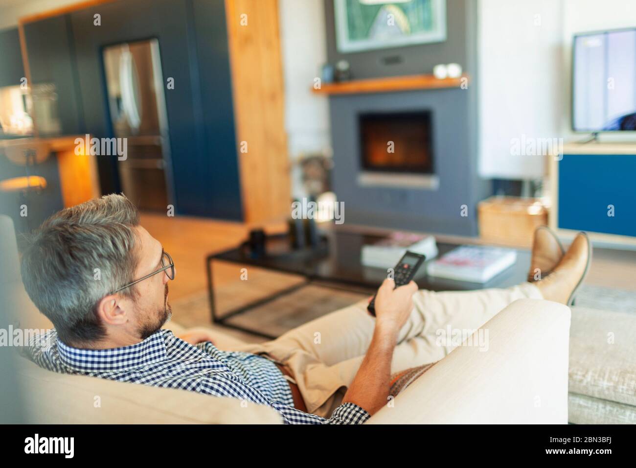 Man relaxing, watching TV in living room Stock Photo