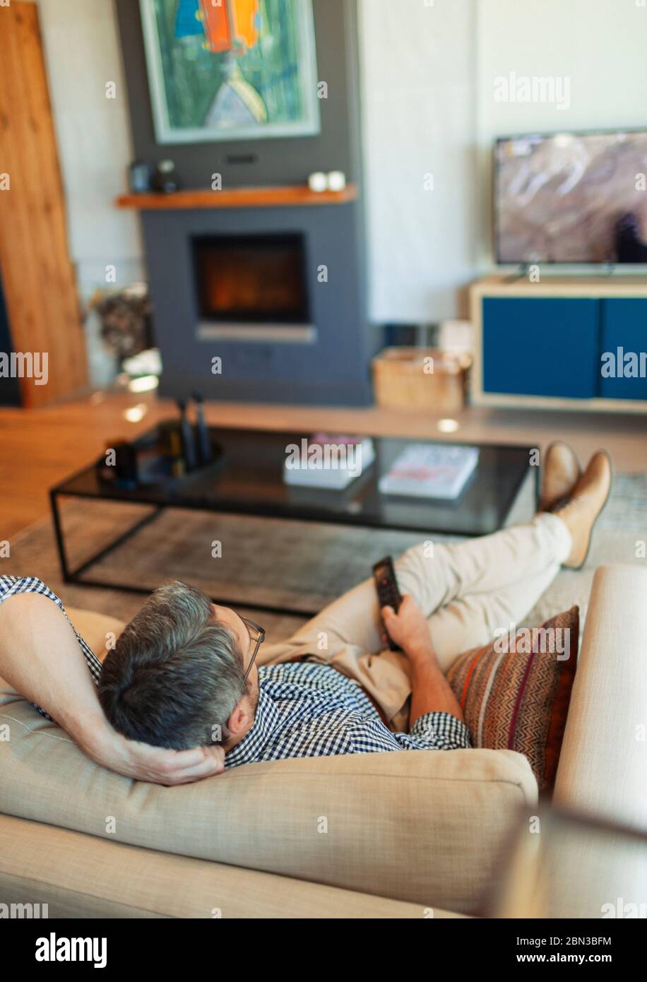 Man relaxing, watching TV on living room sofa Stock Photo Alamy