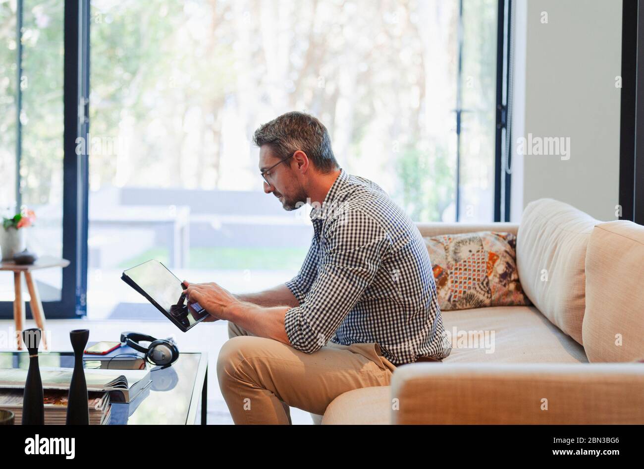 Man using digital tablet on living room sofa Stock Photo