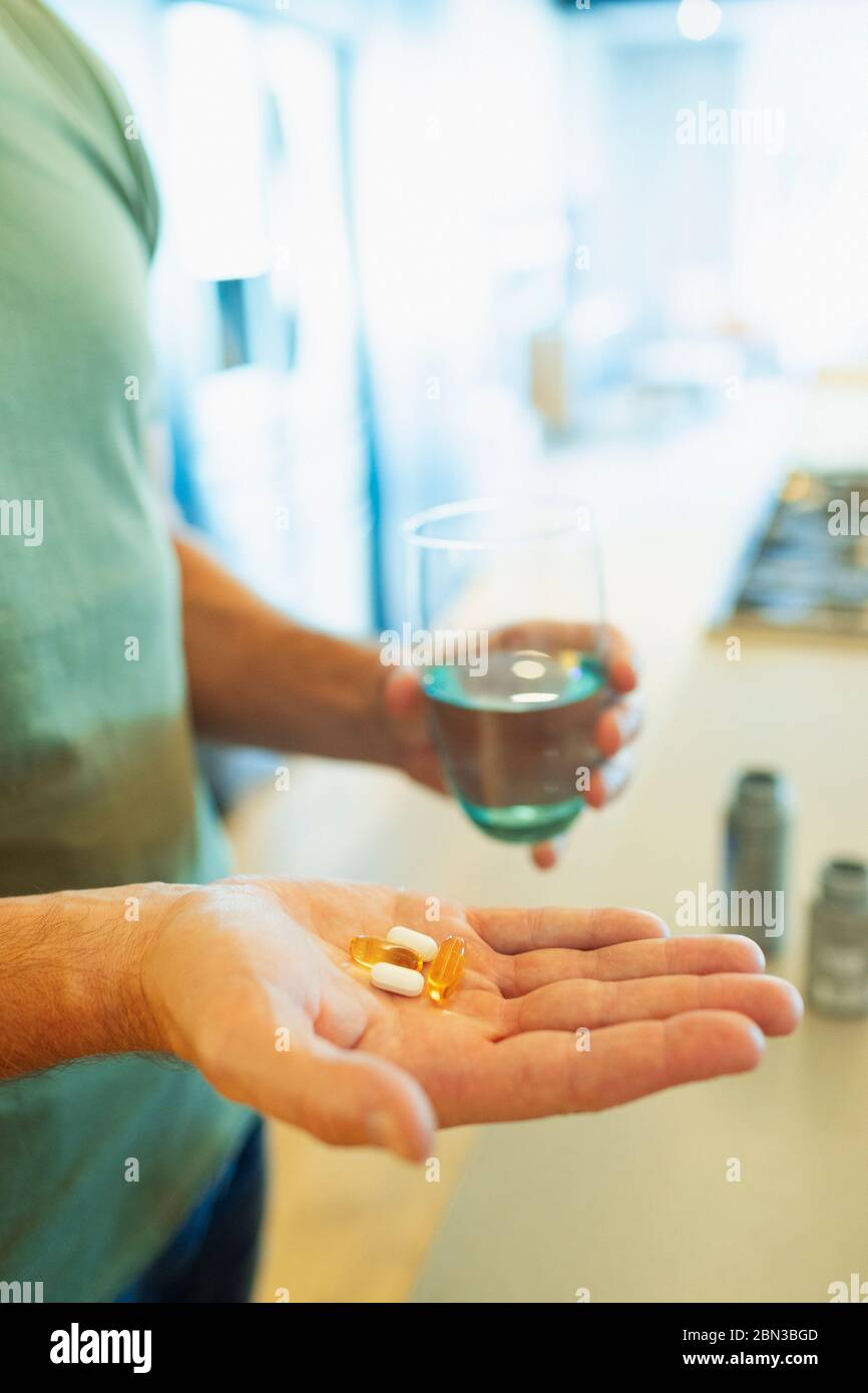 Close up man taking vitamins and supplements with glass of water Stock Photo