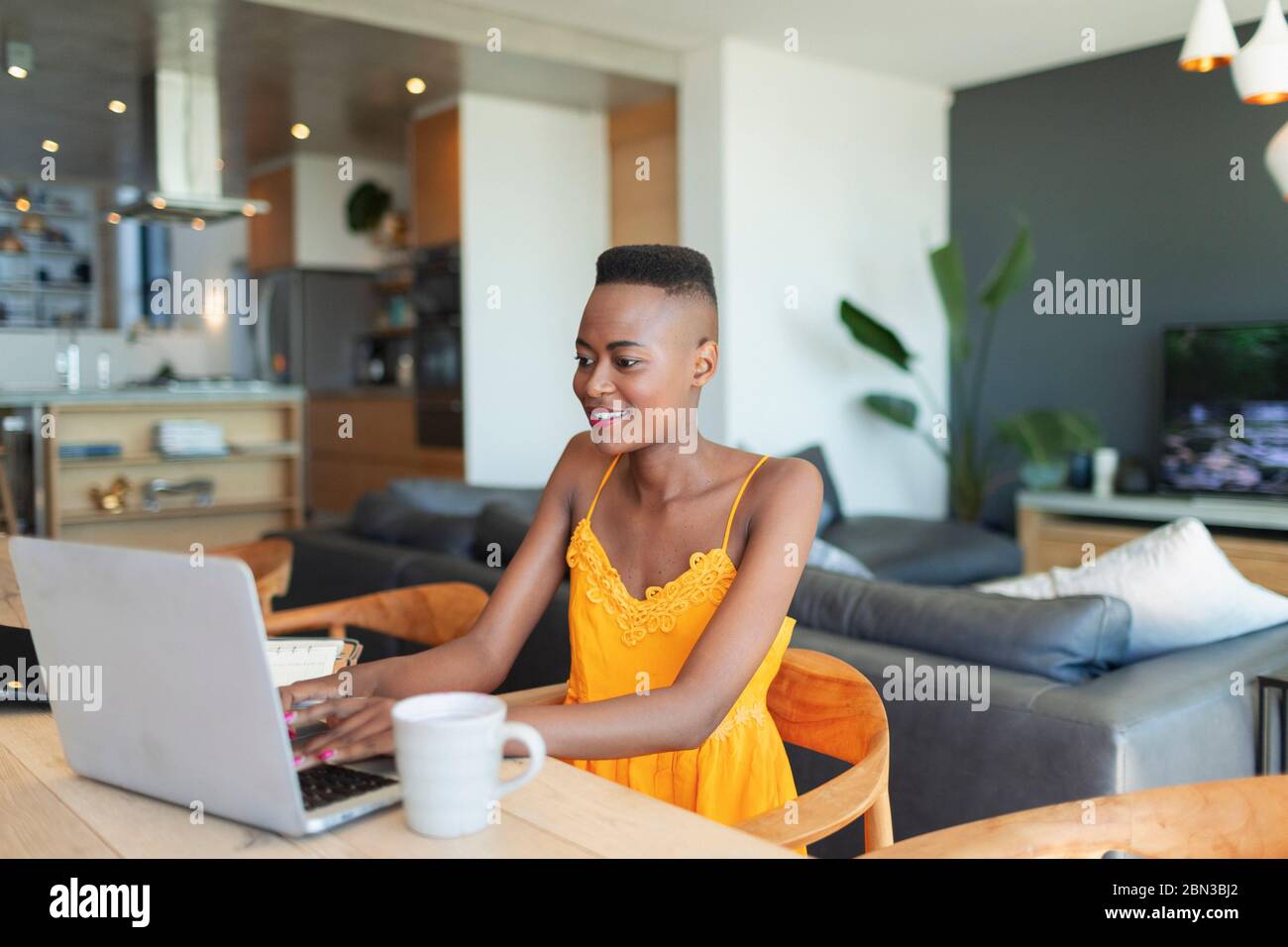 Young woman using laptop, working from home at dining table Stock Photo