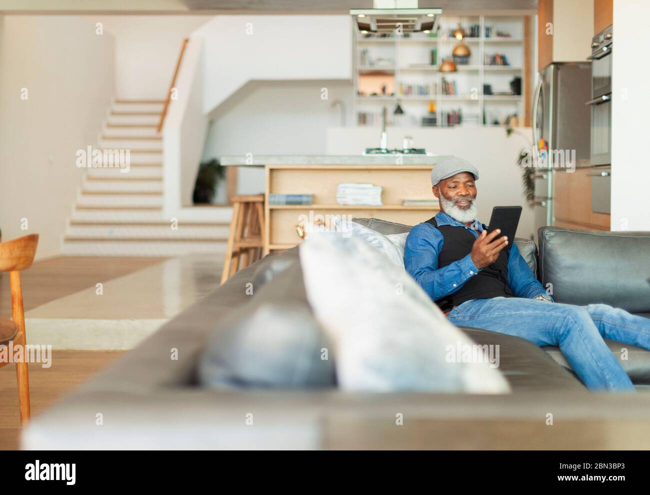 Man using digital tablet on living room sofa Stock Photo
