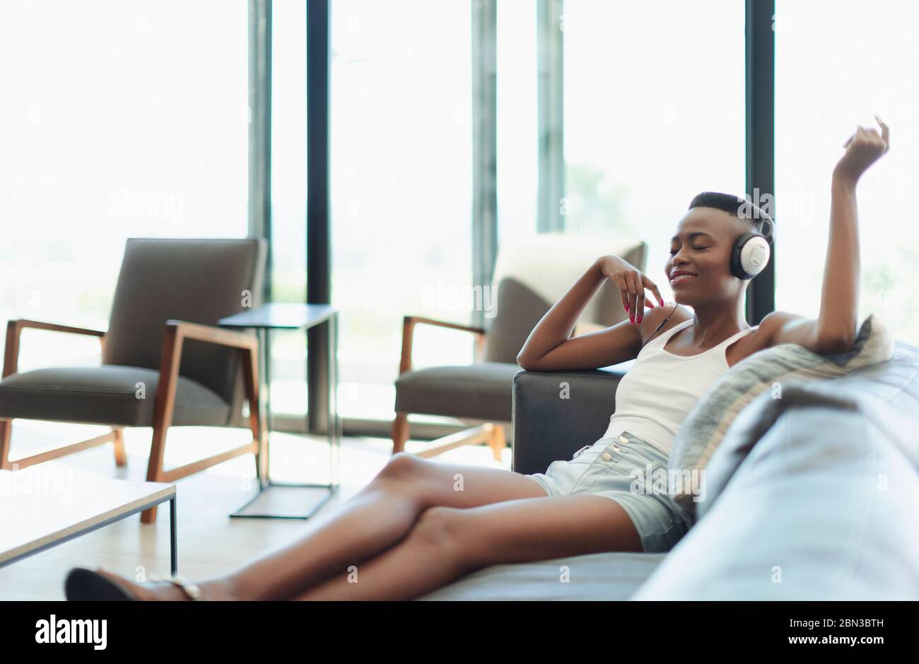 Serene, happy young woman listening to music with headphones on living room sofa Stock Photo