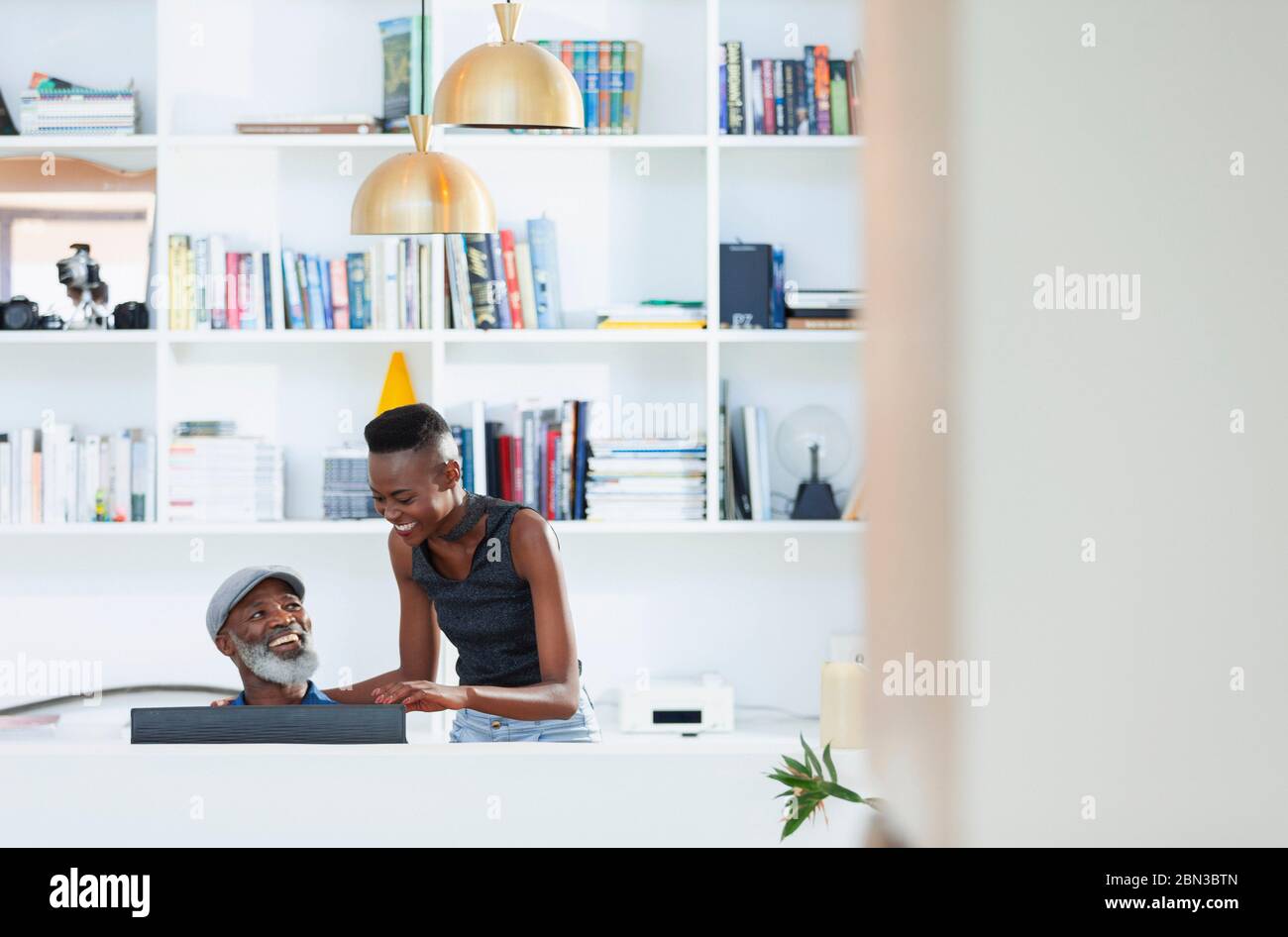 Happy father and daughter talking, using computer in home office Stock Photo