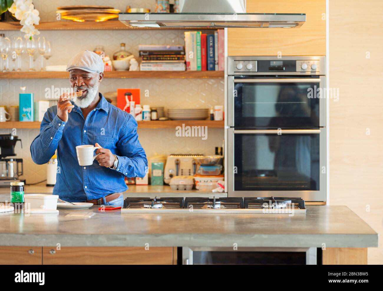 Man enjoying toast and coffee breakfast in modern kitchen Stock Photo