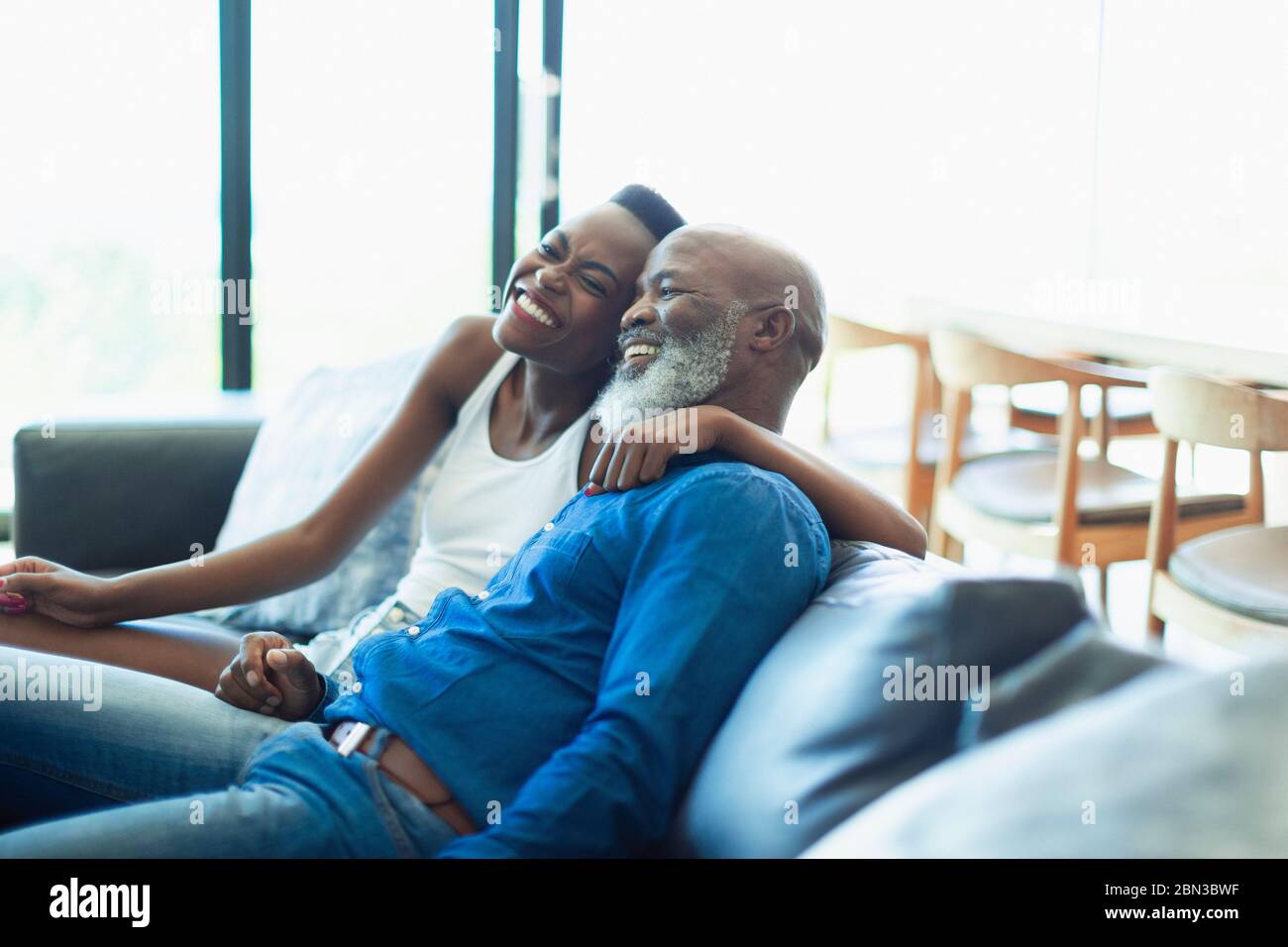 Happy, affectionate father and daughter hugging on living room sofa Stock Photo