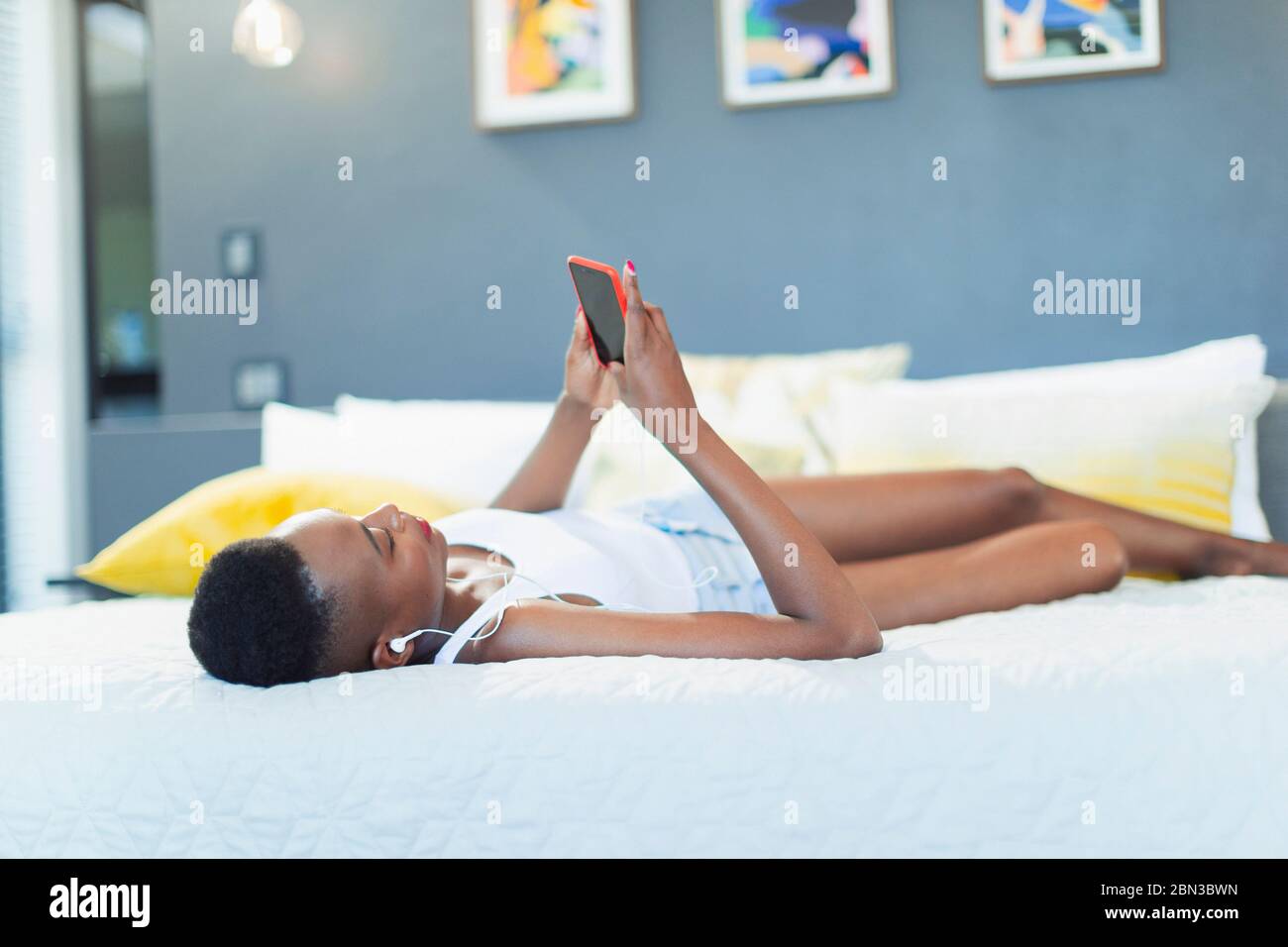 Young woman relaxing on bed, listening to music with mp3 player and headphones Stock Photo