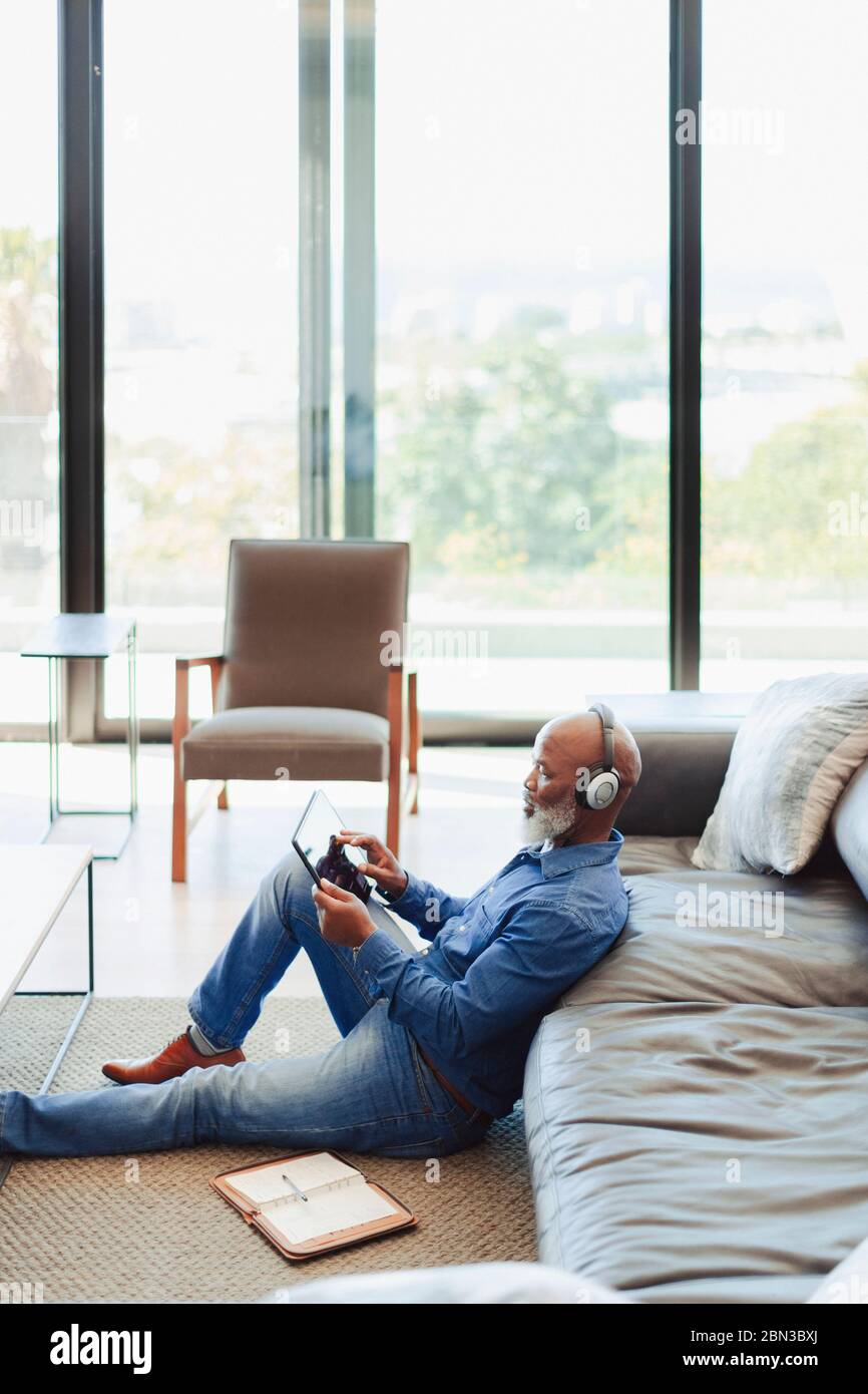 Man with headphones using digital tablet on living room floor Stock Photo