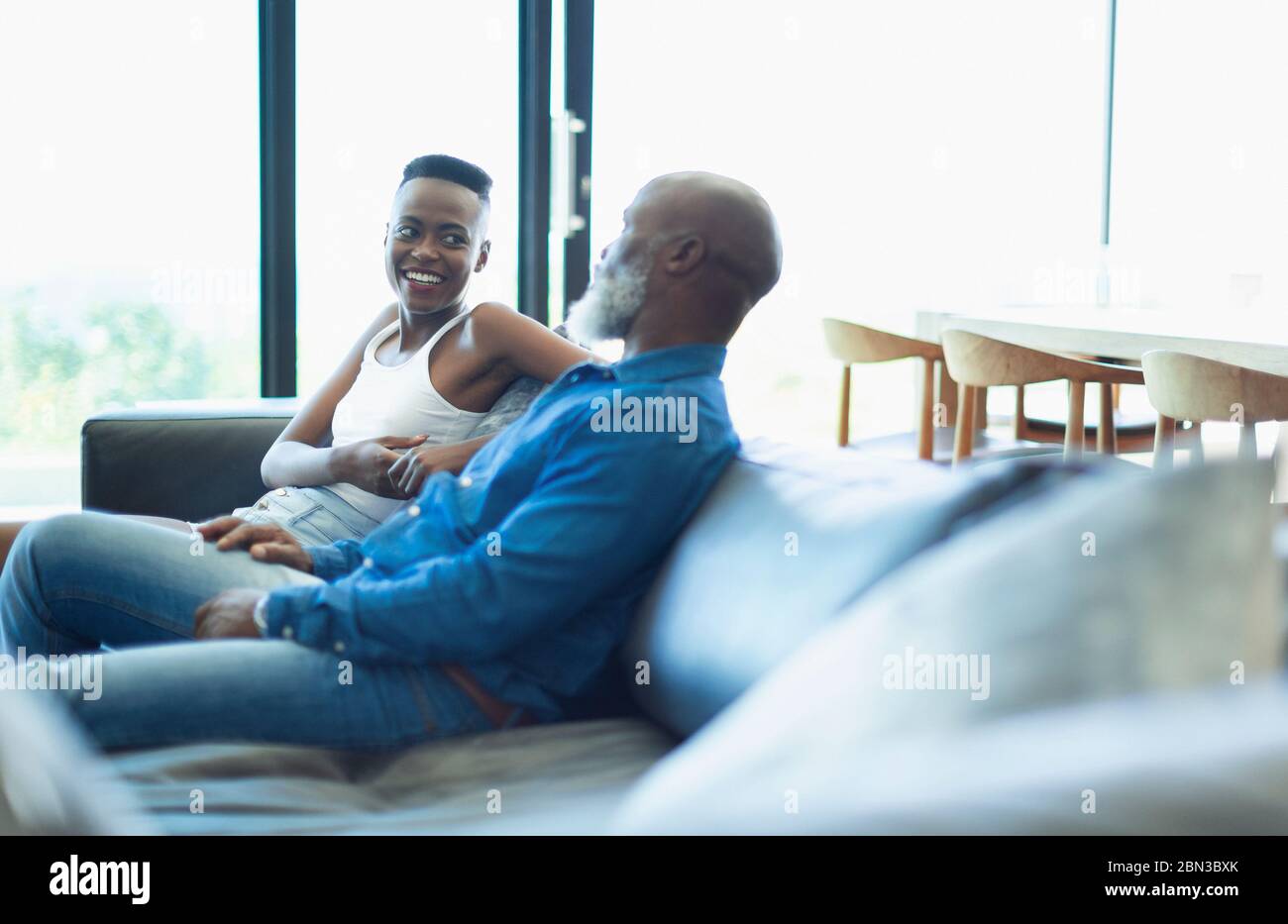 Father and daughter talking on living room sofa Stock Photo