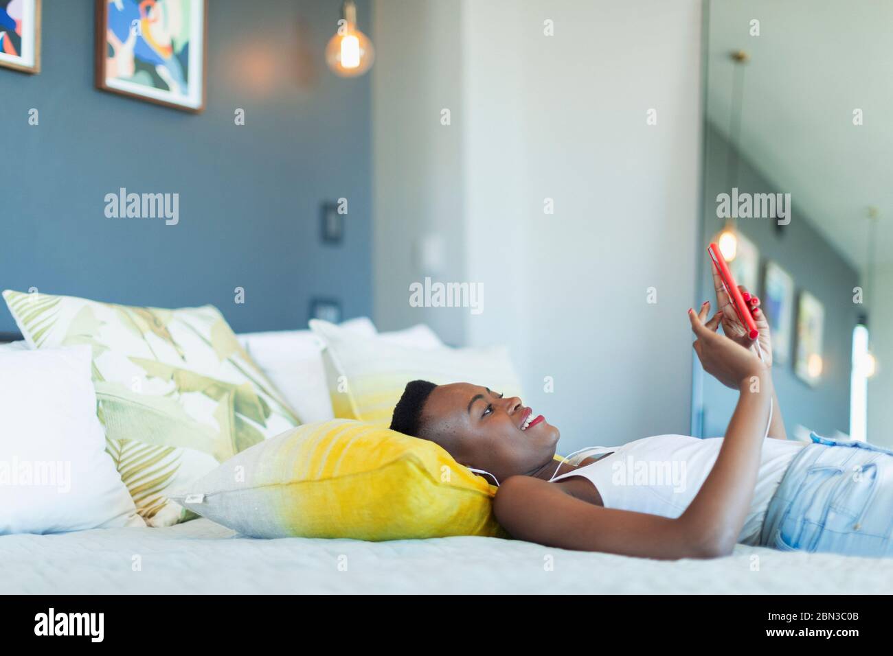 Young woman relaxing on bed, listening to music with headphones and mp3 player Stock Photo
