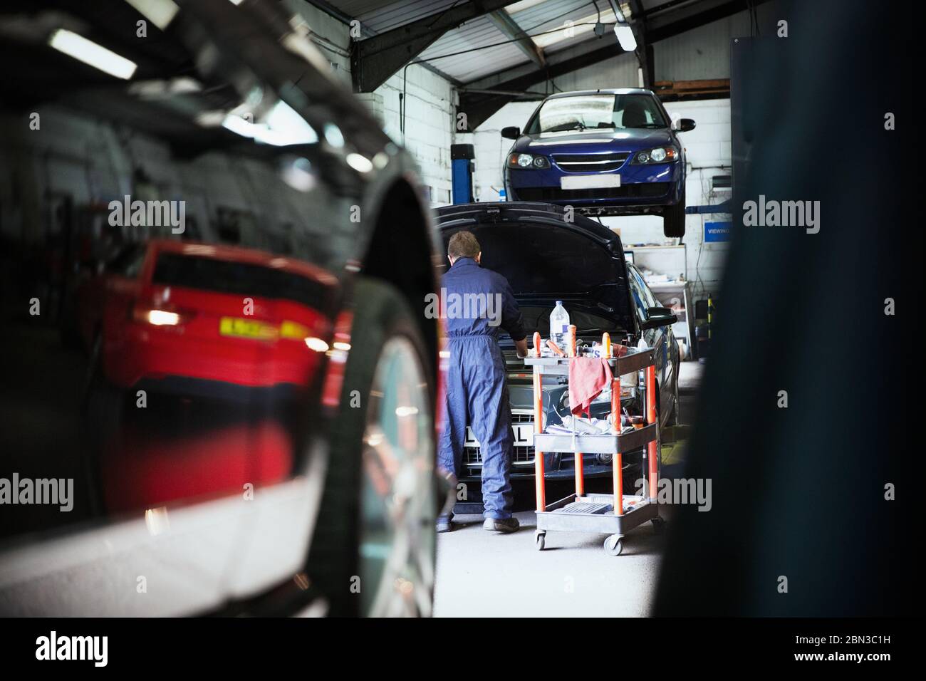 Male mechanic working under automobile hood in auto repair shop Stock Photo