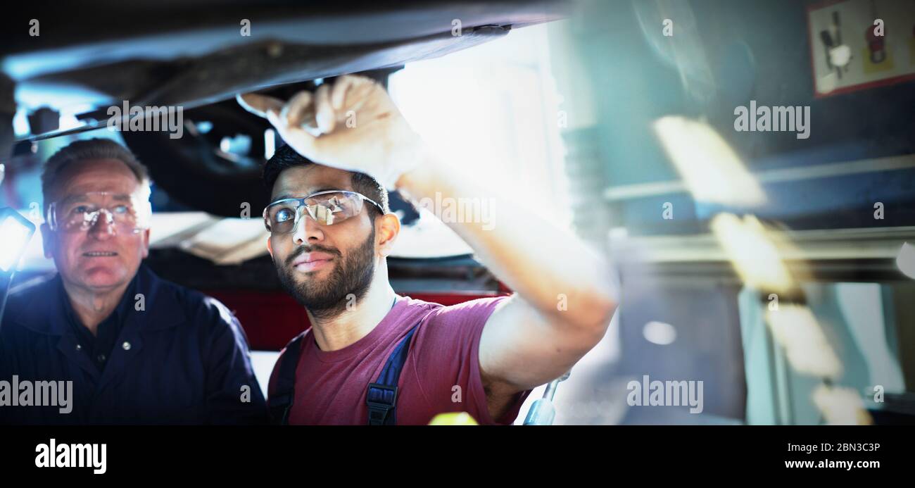 Male mechanics working under car in auto repair shop Stock Photo