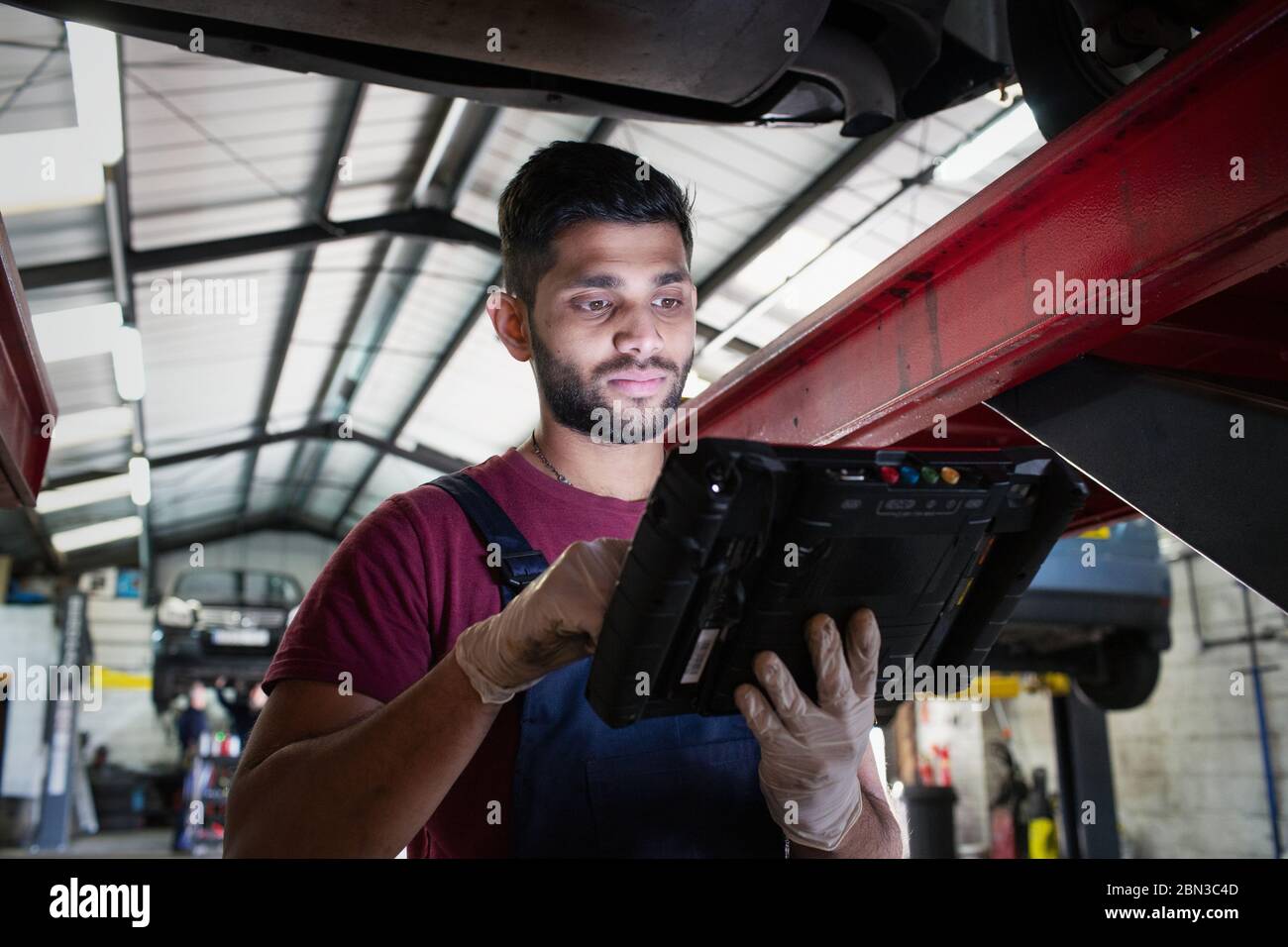 Focused male mechanic using diagnostic equipment in auto repair shop Stock Photo