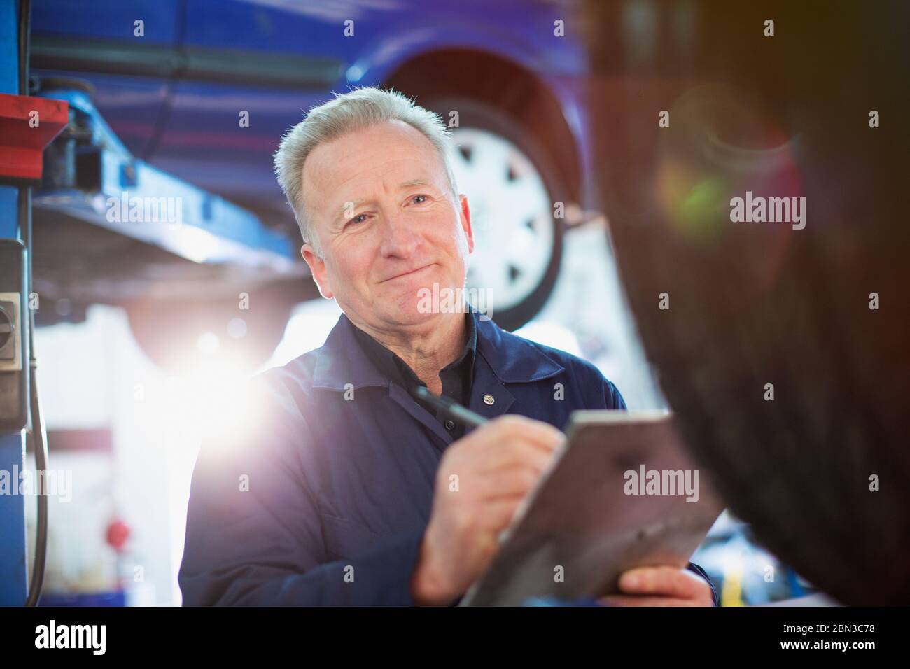 Smiling male mechanic with clipboard working in auto repair shop Stock Photo