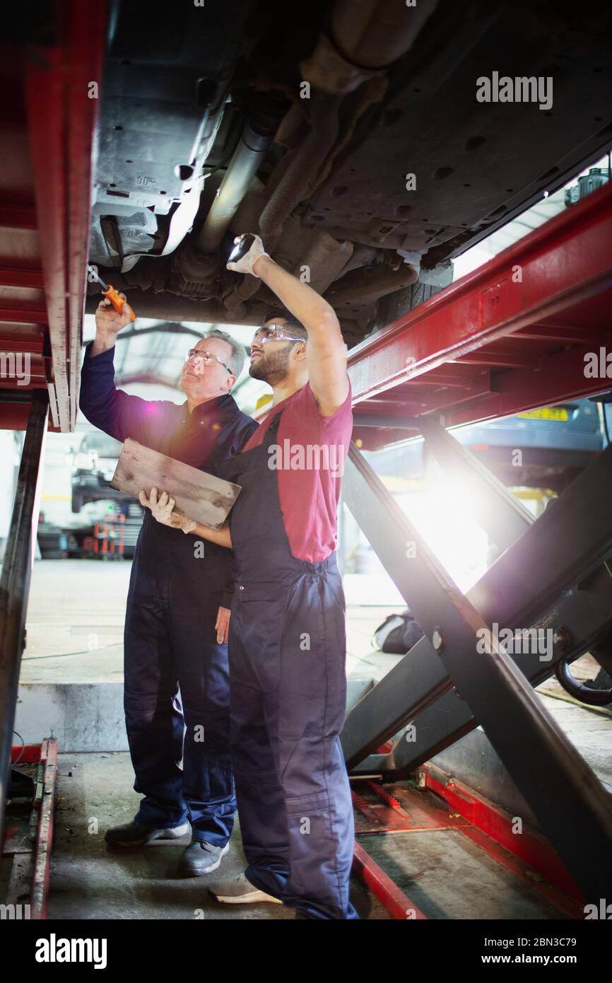 Male mechanics working under car in auto repair shop Stock Photo - Alamy