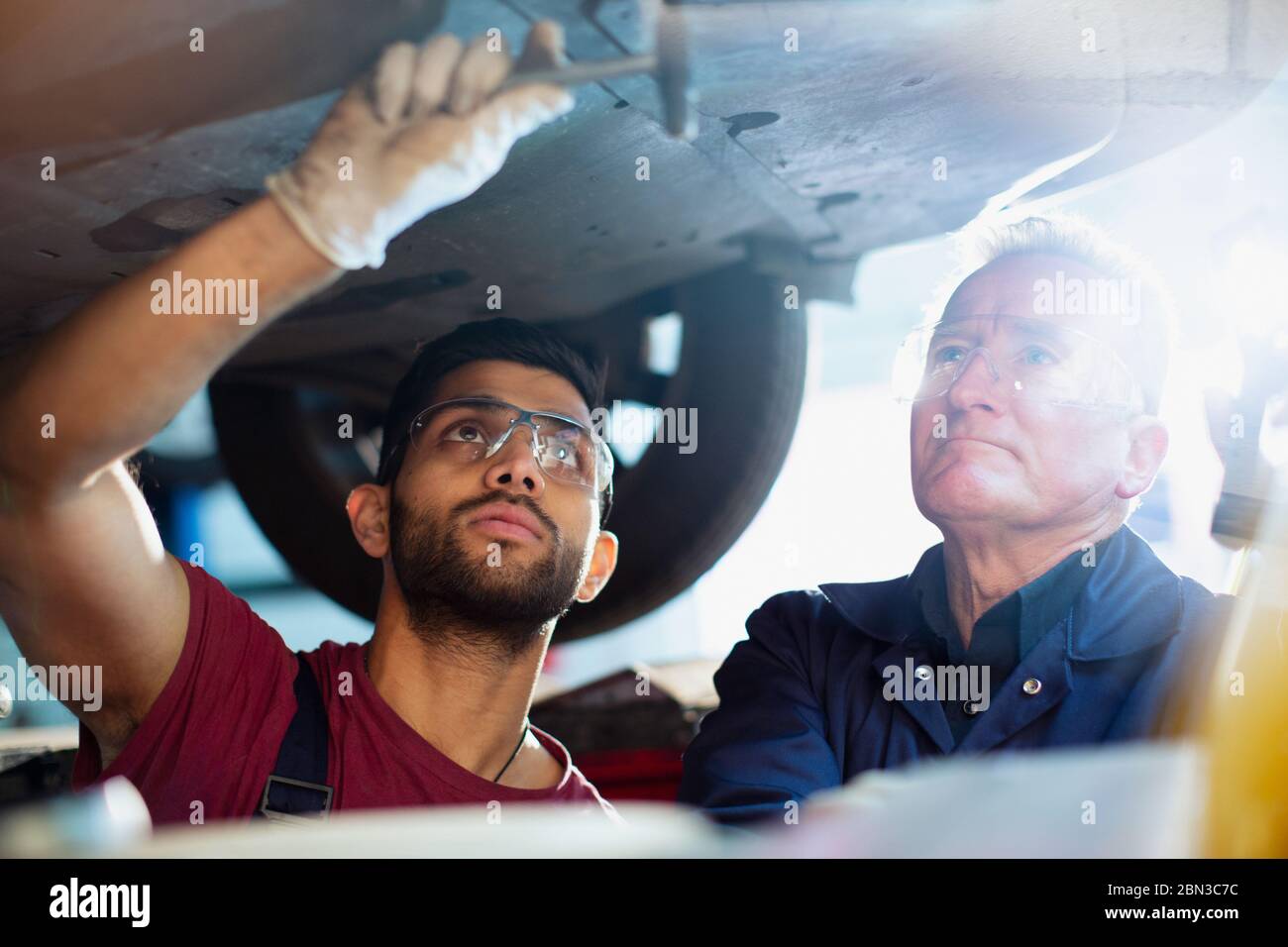 Male mechanics working under car in auto repair shop Stock Photo