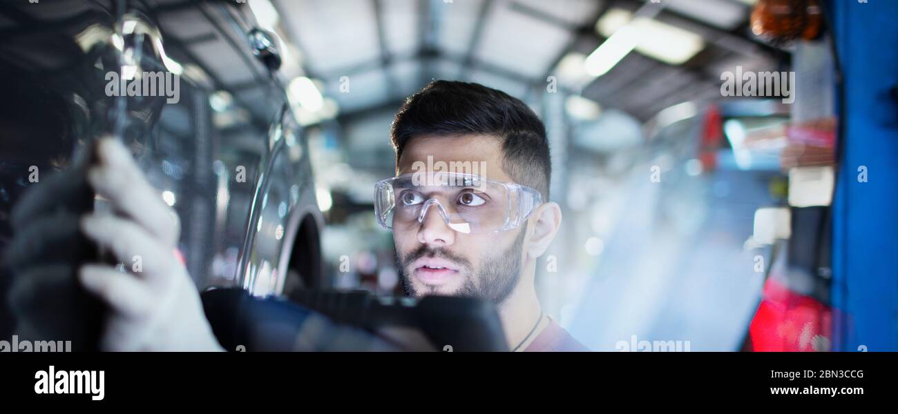 Focused male mechanic examining car in auto repair shop Stock Photo
