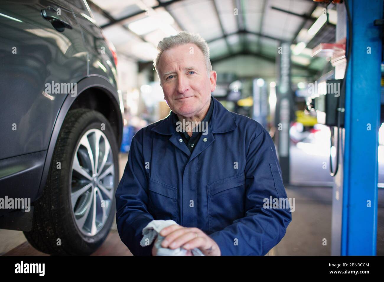 Portrait confident male mechanic wiping hands in auto repair shop Stock Photo