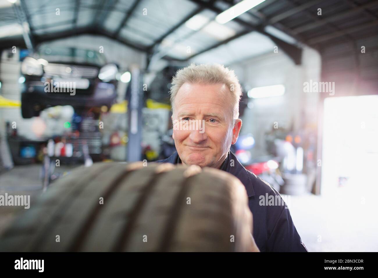 Male mechanic examining tire in auto repair shop Stock Photo