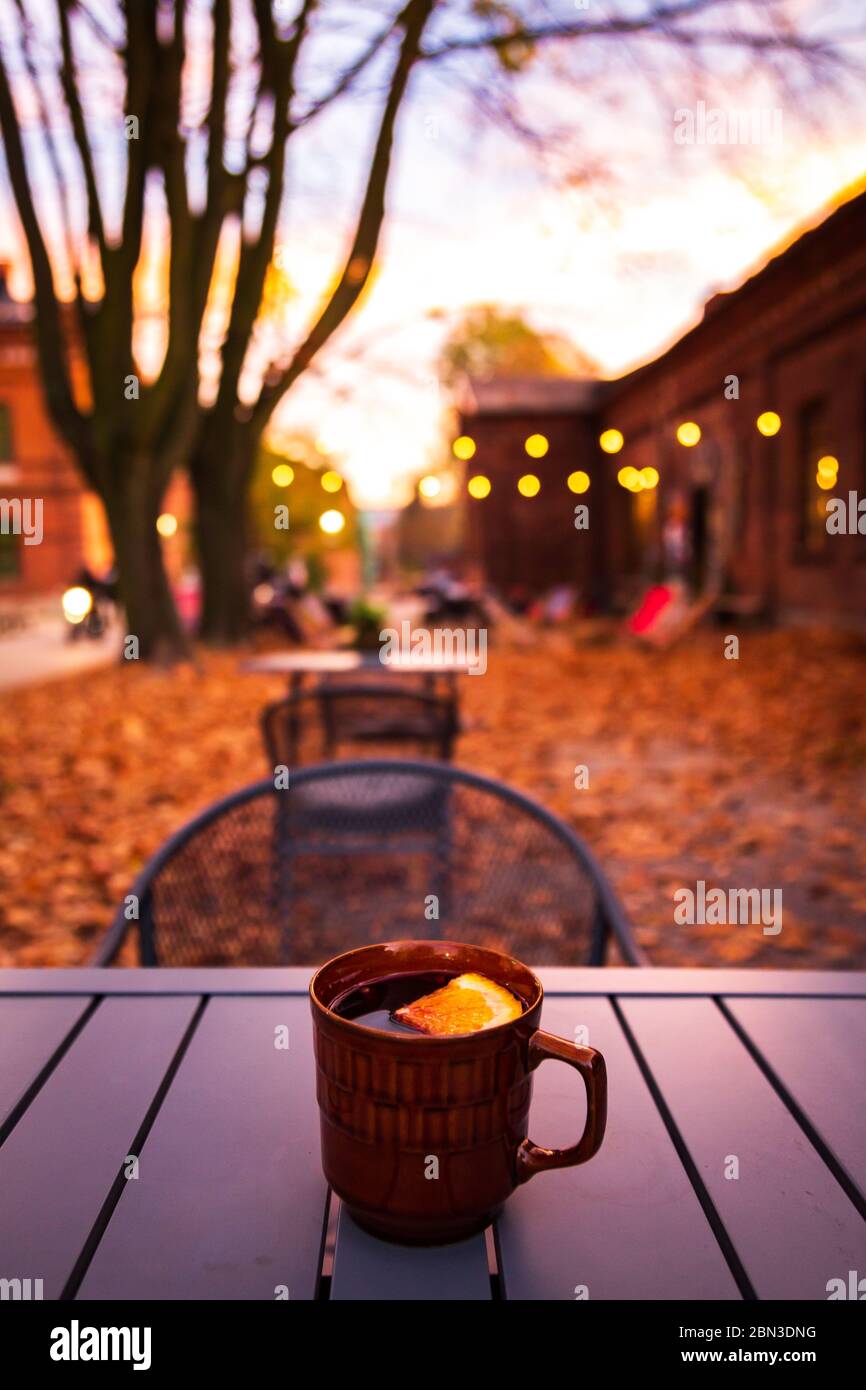 Lodz, Poland: A cup of hot drink on the table in the Ksiezy Mlyn historic distric during autumn evening Stock Photo