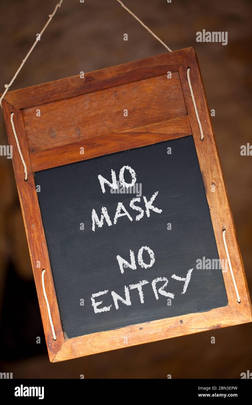 No Mask No Entry Coronavirus COVID-19 pandemic wooden blackboard or chalkboard menu sign hanging in a retail shop, restaurant or cafe Stock Photo