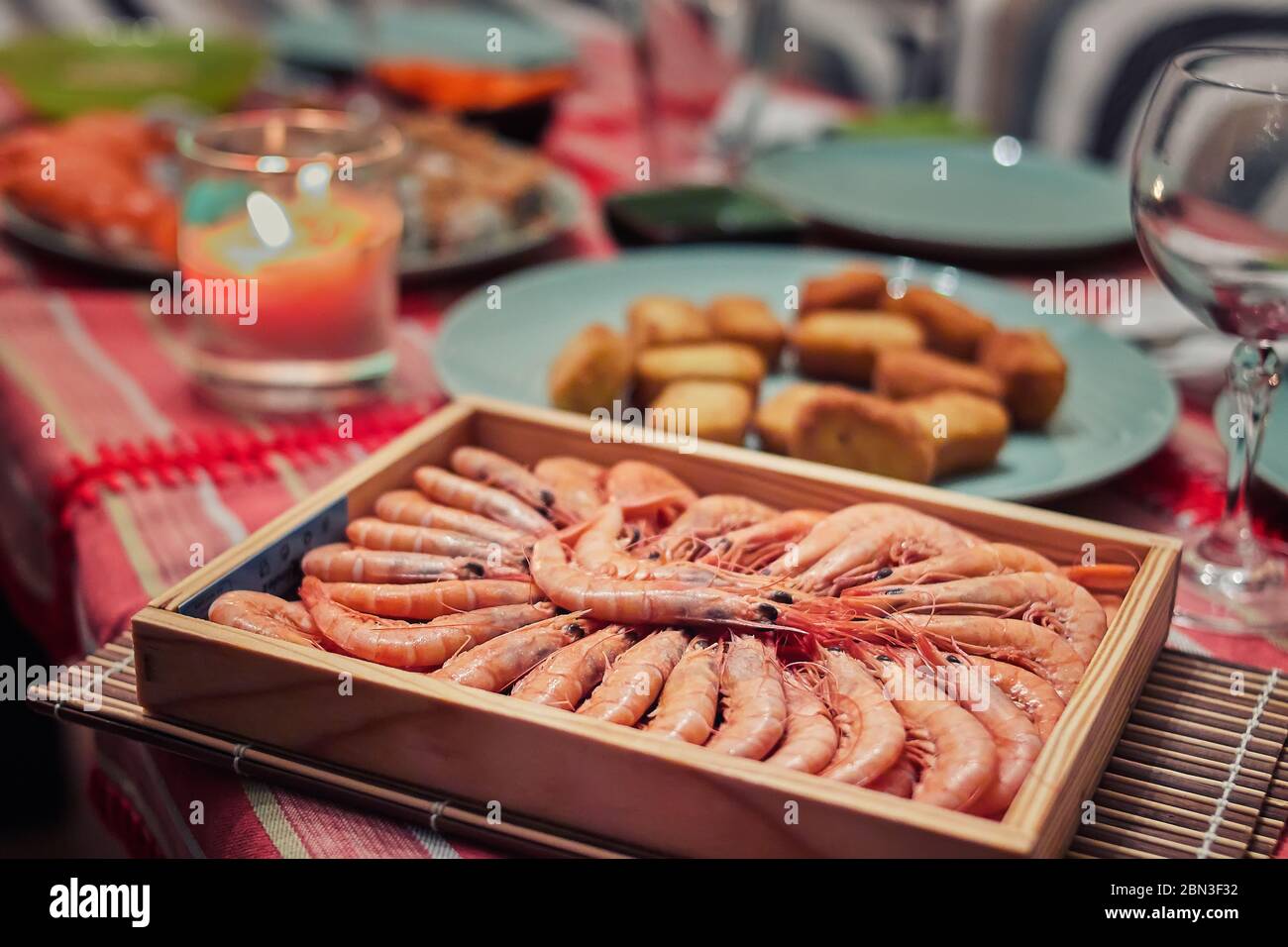 Boiled prawns wood box in a table for dinner, with a glass cup and a candle Stock Photo
