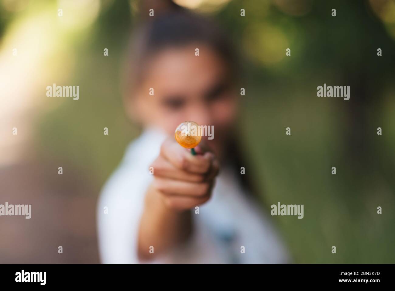 The girl shows the candy on a stick in the frame.  Stock Photo