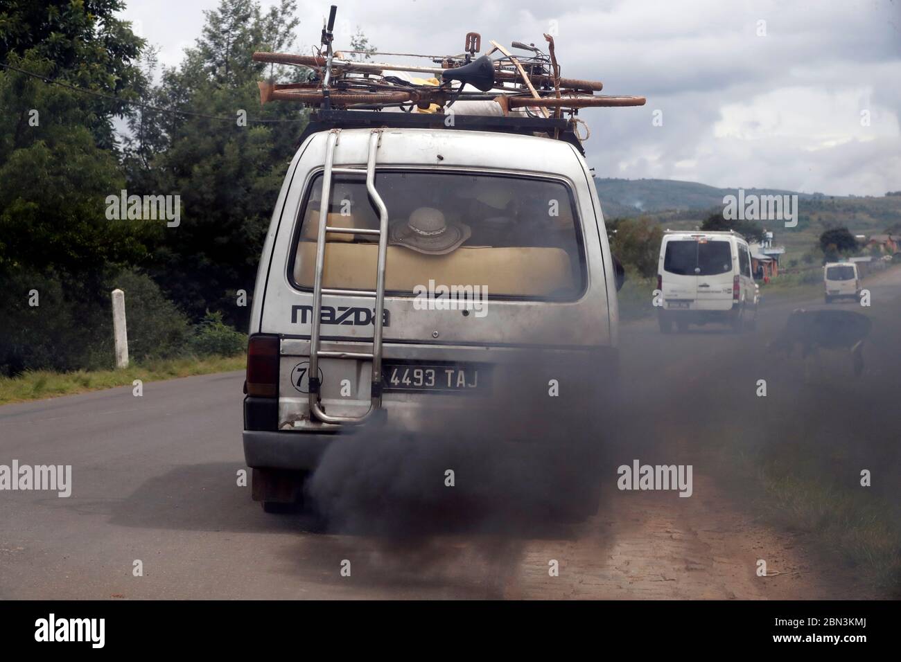 Old minibus emitting black smoke on road. Pollution.  Antsirabe. Madagascar. Stock Photo