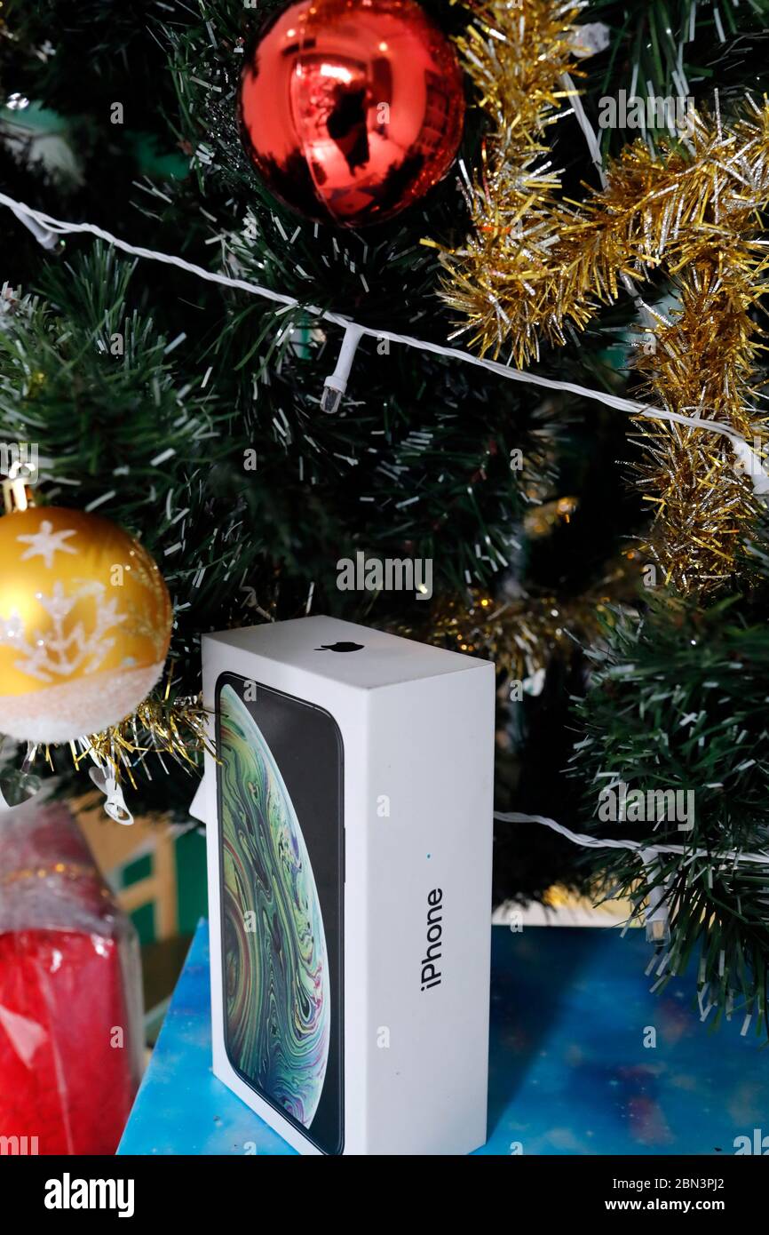 Presents under the decorated artificial Christmas tree.  Iphone box. Stock Photo