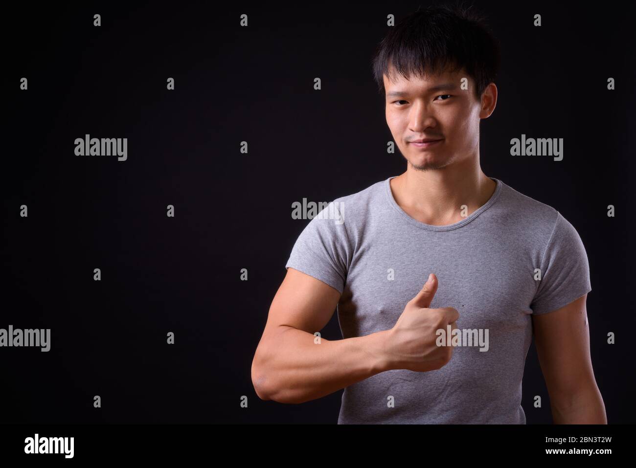 Portrait of young Asian man giving thumbs up Stock Photo - Alamy