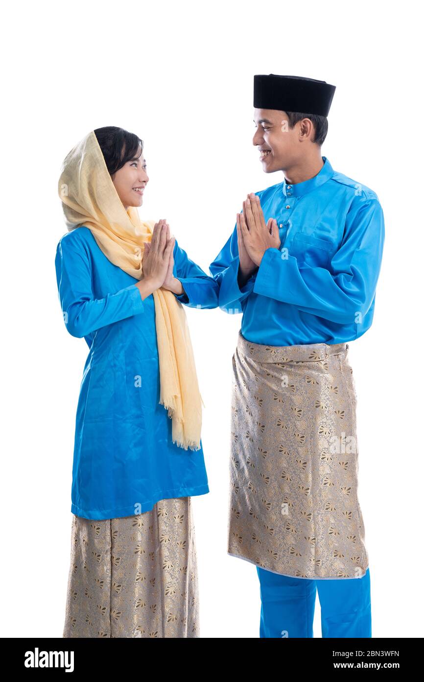 muslim malay couple with greeting gesture over white background. wishing you eid mubarak Stock Photo