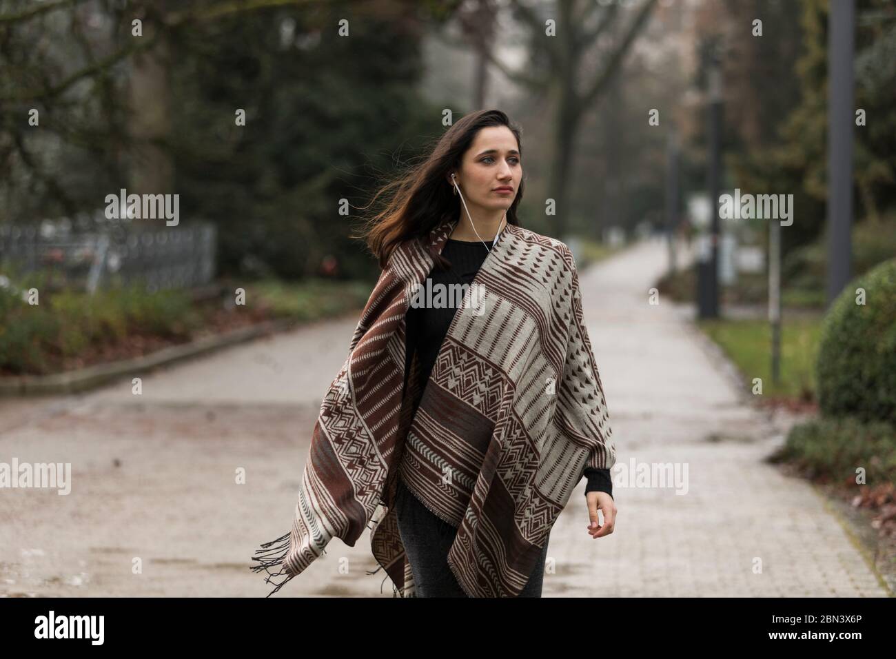 Young Indian woman wearing poncho walking outdoors with head turned looking  away Stock Photo - Alamy