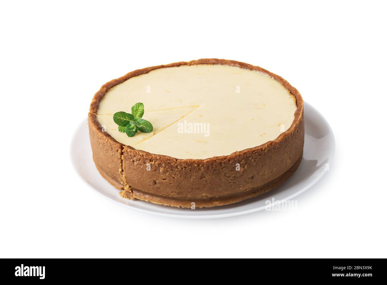 Plane round classic New York cheesecake with sprig of mint on a plate isolated on white background Stock Photo