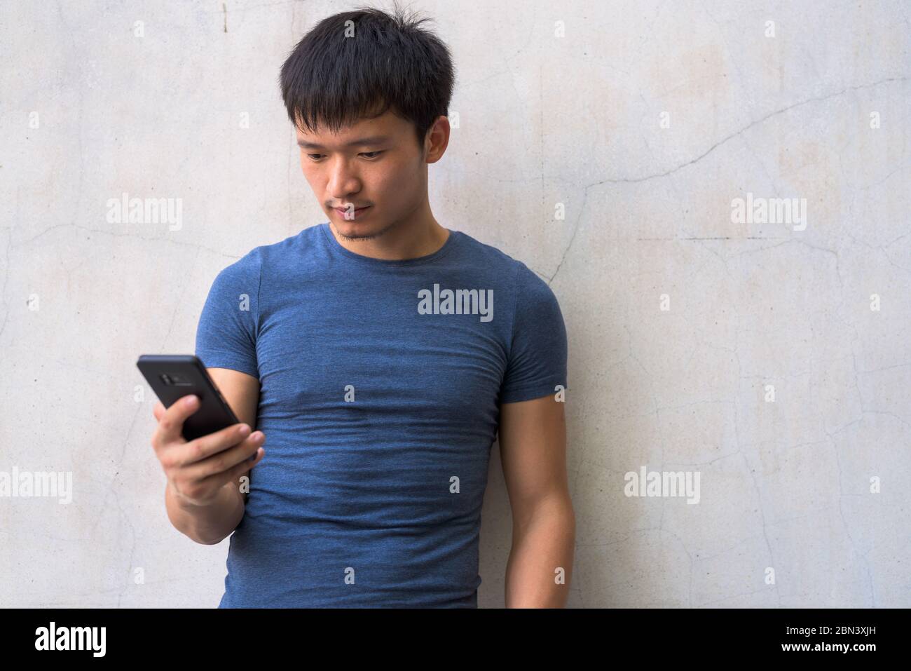 Portrait of young Asian man using phone outdoors Stock Photo