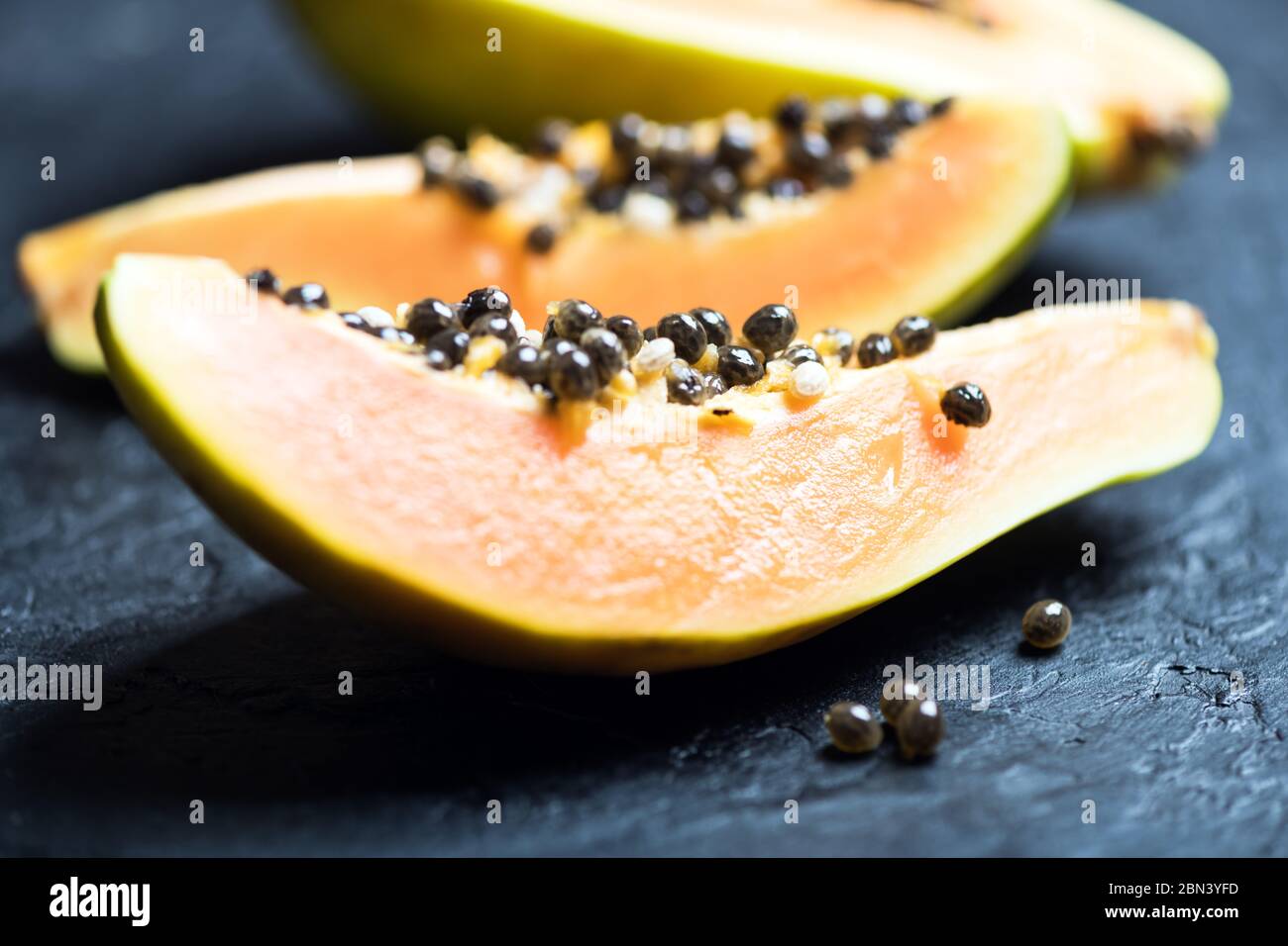 Slised papaya with silver spoon on black concrete background. Food photography Stock Photo